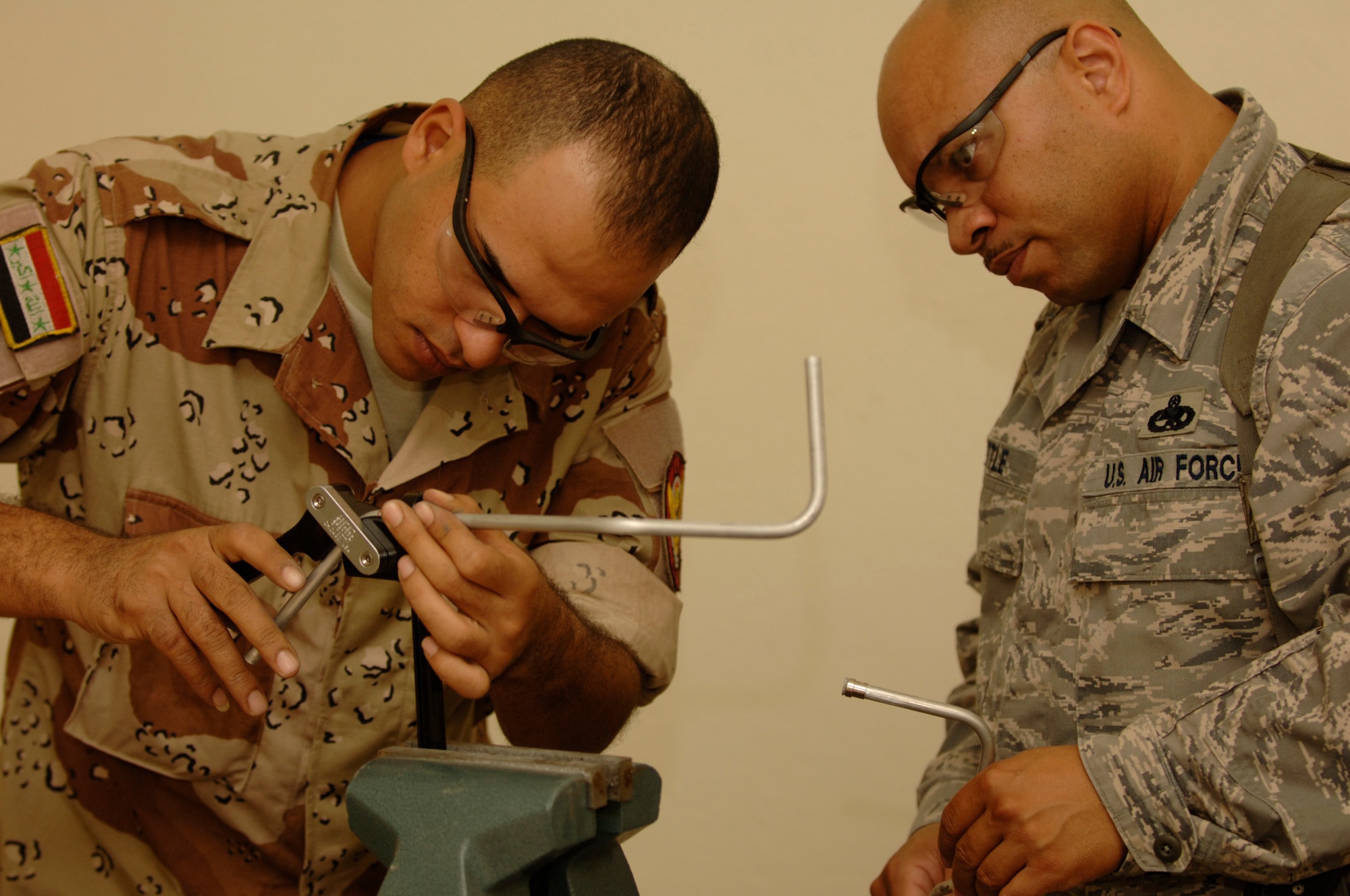 TAJI, Iraq -- Master Sgt. Joel Little watches Iraqi air force warrant officer Omar Saaed bend a piece of metal tubing during the fabrication portion of the aircraft structural maintenance course at Al-Taji Air Base, Iraq. Little is deployed with the 821st Air Expeditionary Training Squadron. (U.S. Air Force photo/Staff Sgt. Paul Villanueva II)