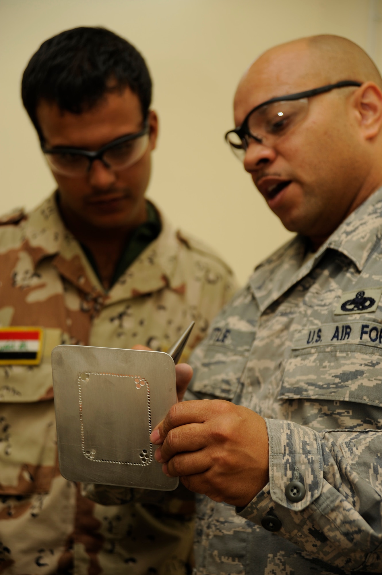 TAJI, Iraq -- Master Sgt. Joel Little shows Iraqi air force warrant officer Hussen Mohammad how to chain drill a damaged section of aircraft for removal and replacement at Al-Taji Air Base, Iraq. Little, a Charlotte, N.C. native, is deployed with the 821st Air Expeditionary Training Squadron where he is the aircraft structural maintenance instructor. (U.S. Air Force photo/Staff Sgt. Paul Villanueva II)