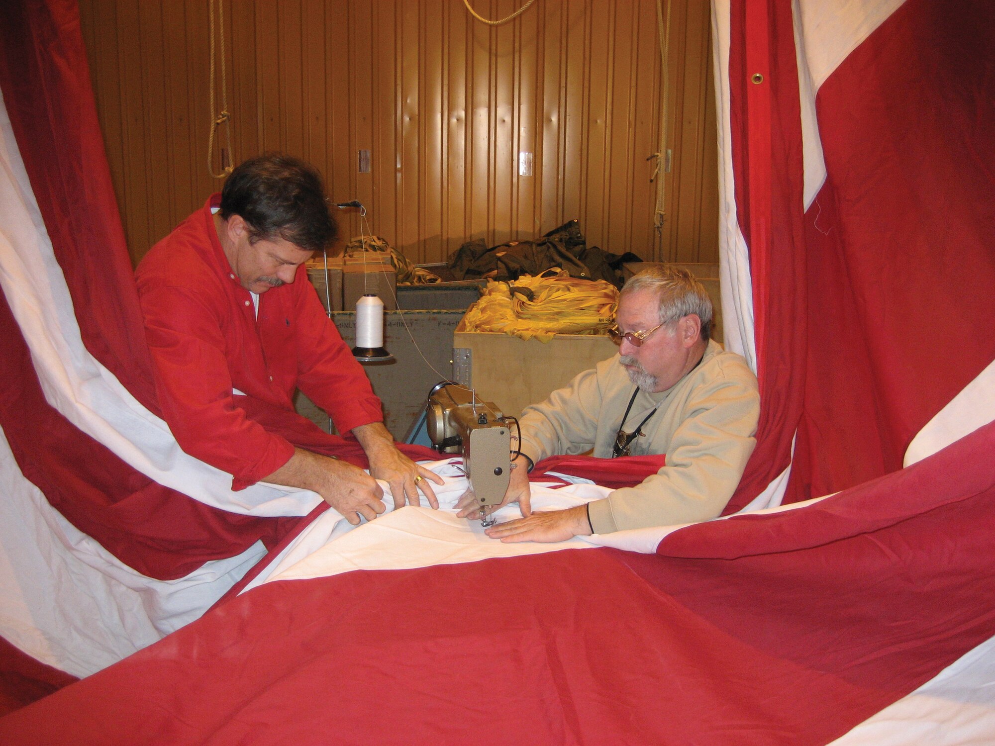 Parachute riggers David Weiss and Gary Wood repair a hole in Tinker’s garrison flag, getting it ready for the Oklahoma City Air Logistics Center change of command Wednesday. (Courtesy photo)