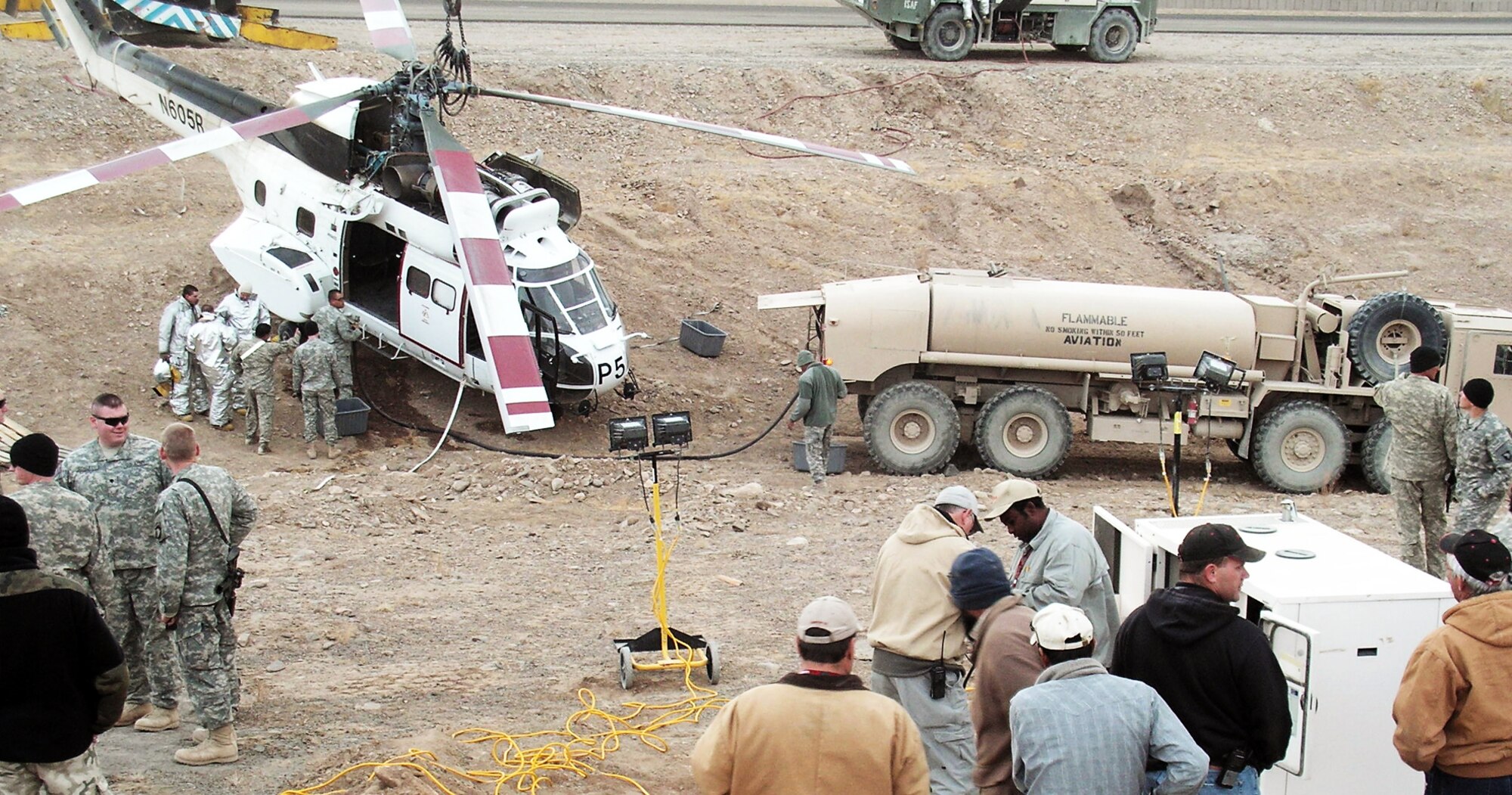 Emergency response workers and forward operating base personnel prepare a helicopter for removal after it crashed in a ditch Dec. 15 at an air base in Southwest Asia. Firefighters from the 379th Expeditionary Civil Engineer Squadron were the first on scene. (Courtesy photo) 
