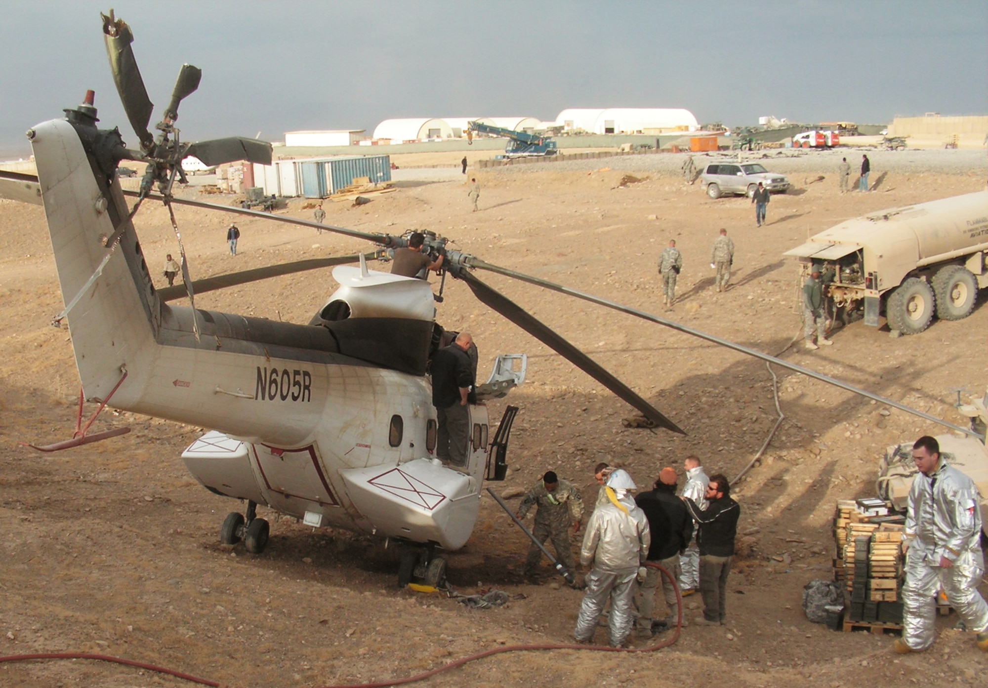 Emergency response workers and forward operating base personnel prepare a helicopter for removal after it crashed in a ditch Dec. 15 at an air base in Southwest Asia. Firefighters from the 379th Expeditionary Civil Engineer Squadron were the first on scene. (Courtesy photo) 
