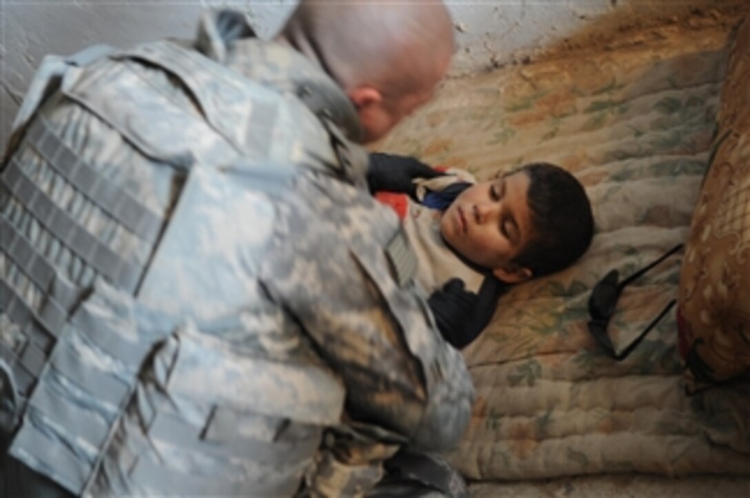 Spc. Tommy Marino from Charlie Company, 2nd Infantry Battalion, 35th Infantry Regiment, 3rd Brigade Combat Team, 25th Infantry Division performs first aid on an injured Iraqi boy in Samarra, Iraq, on Dec. 30, 2008.  