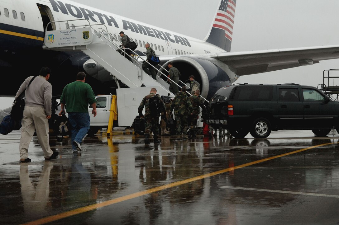 LANGLEY AFB, Va. -- Langley Airmen board a commercial aircraft in the rain Jan. 6. More than 250 Airmen departed for Kadena Air Base, Japan, as part of a theater security package being sent to the Western Pacific. (U.S. Air Force photo/Senior Airman Cecil C. McCloud)
