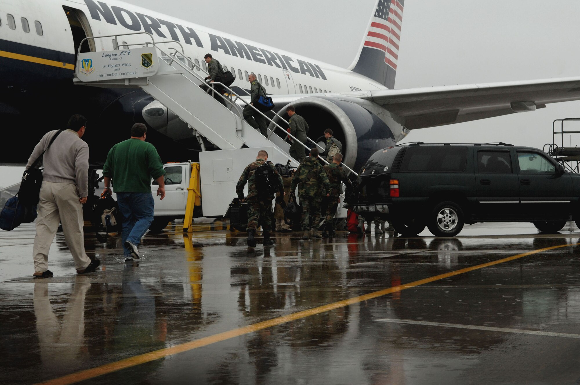 LANGLEY AFB, Va. -- Langley Airmen board a commercial aircraft in the rain Jan. 6. More than 250 Airmen departed for Kadena Air Base, Japan, as part of a theater security package being sent to the Western Pacific. (U.S. Air Force photo/Senior Airman Cecil C. McCloud)
