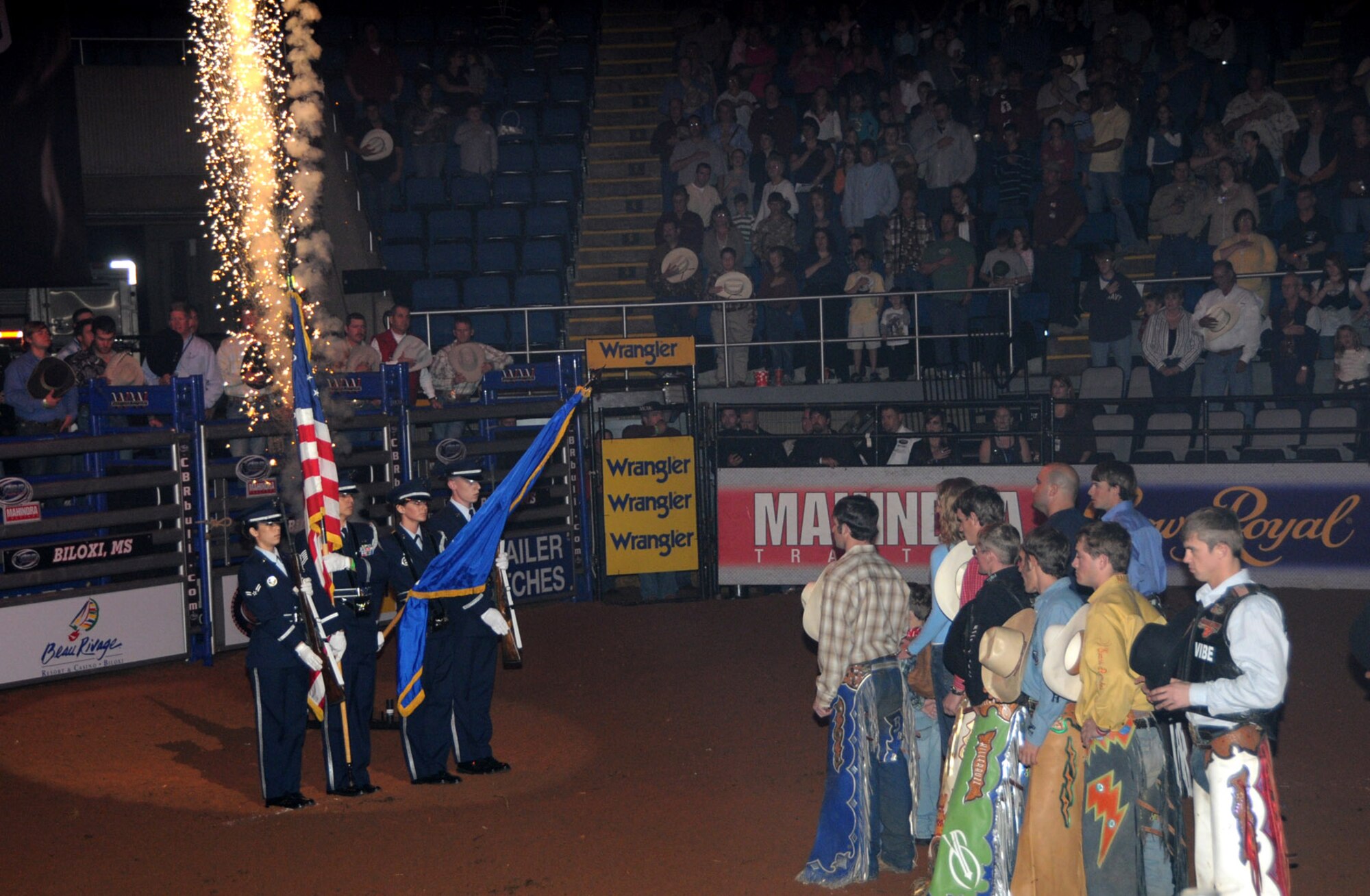Cowboys stand at attention as the Keesler Honor Guard presents the American flag during the playing of the National Anthem at Saturday’s Championship Bull Riding competition at the Mississippi Coast Coliseum in Biloxi.  (U.S. Air Force photo by Kemberly Groue)
