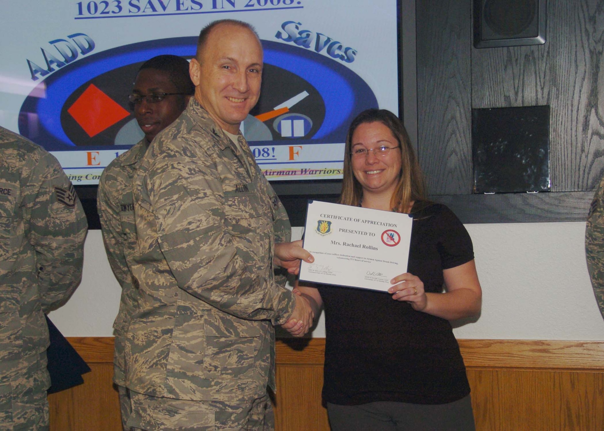 ALTUS AIR FORCE BASE, Okla. -- Mrs. Rachael Rollins (r), 97th Force Support Squadron, receives a wing coin and certificate from Col. David Allvin, 97th Air Mobility Wing commander Jan. 6. Mrs. Rollins was recognized for volunteering 50 hours to the Airmen Against Drunk Driving program. (U.S. Air Force photo/ Airman 1st Class Tiffany M. Deuel)