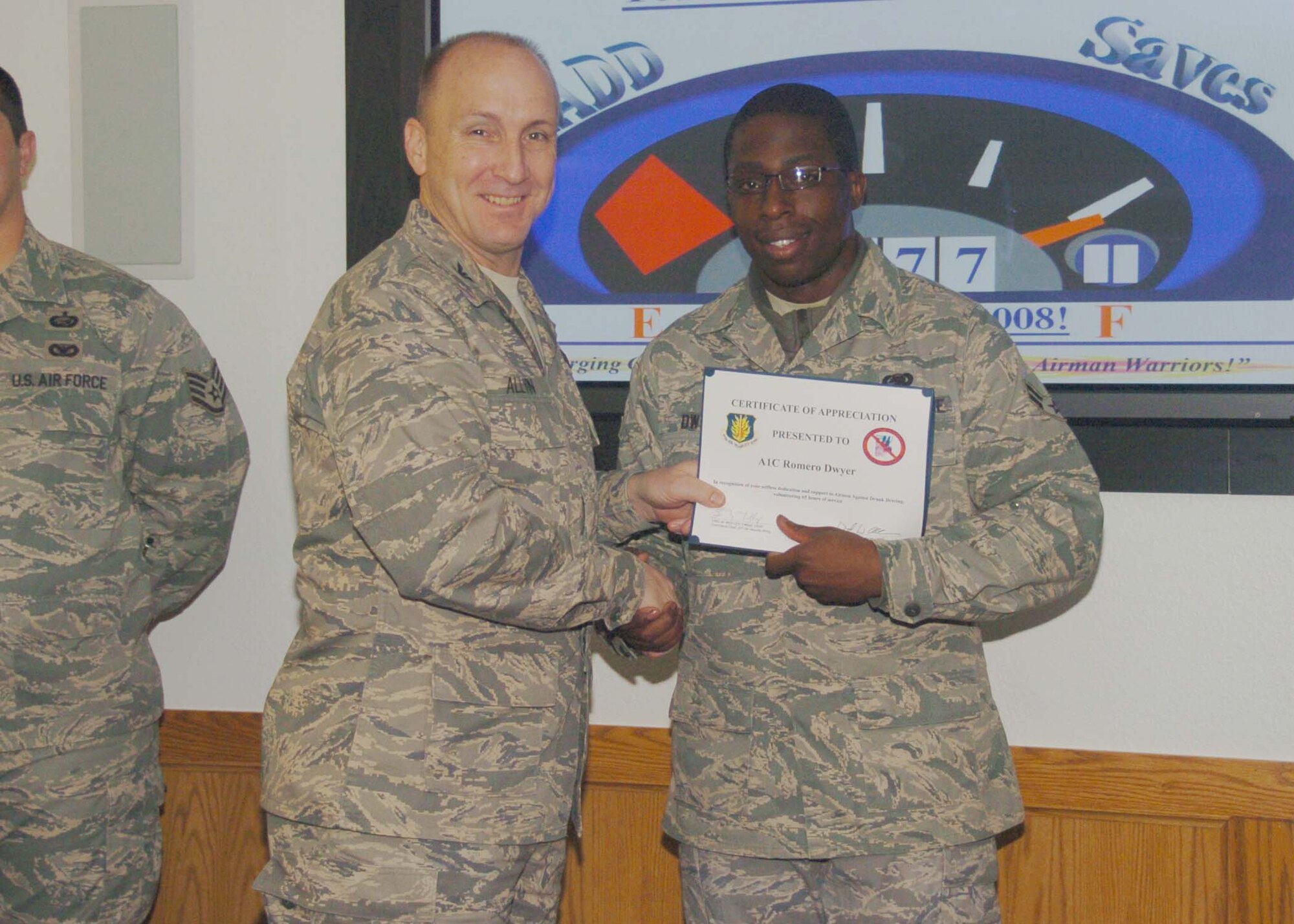 ALTUS AIR FORCE BASE, Okla. -- Airman First Class Romero Dwyer (r), 97th Logistics Readiness Squadron, receives a wing coin and certificate from Col. David Allvin, 97th Air Mobility Wing commander Jan. 6. Airman Dwyer was recognized for volunteering 50 hours of time to help the Airmen Against Drunk Driving effort to curb drunk driving. (U.S. Air Force photo/ Airman 1st Class Tiffany M. Deuel)