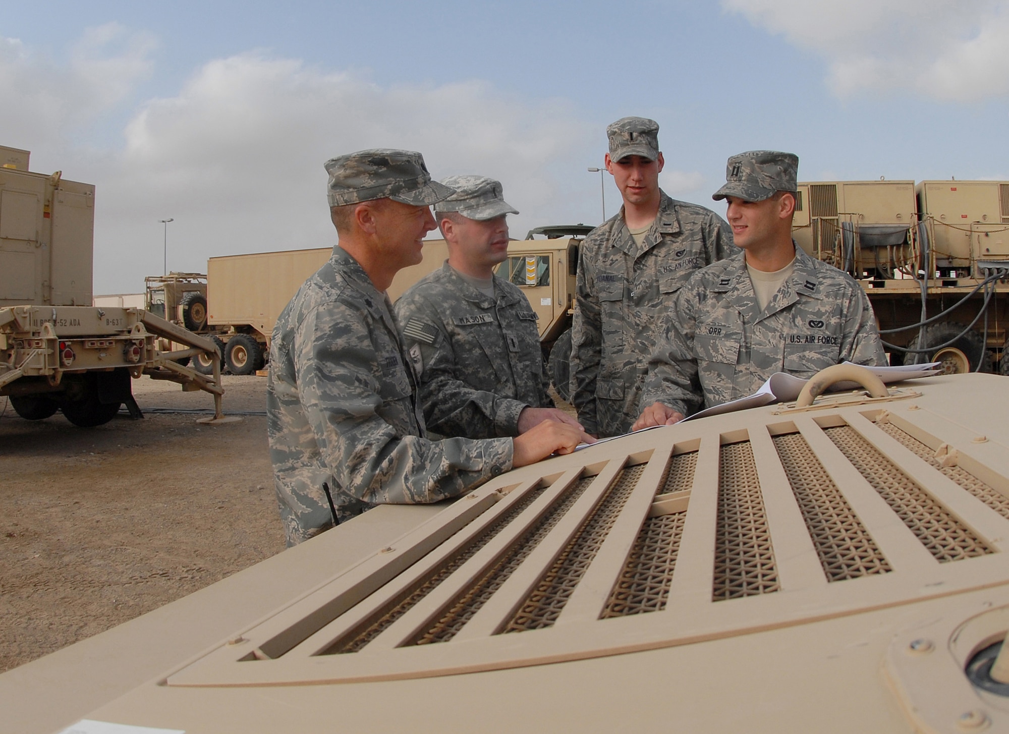 Lt. Col. Fred Thaden (left to right), Army 1st Lt. Erik Mason, 1st Lt. Shawn McDanal and Capt. Raymond Orr gather at the Patriot Battery motor pool to go over ground plans in preparation for the arrival of about 200 Soldiers in the coming weeks Jan. 3 at an air base in Southwest Asia. The advance team of Soldiers, in addition to the arrival of the main body, will comprise the first Patriot Battery at the 380th Air Expeditionary Wing. Colonel Thaden is the 380th Expeditionary Mission Support Group deputy commander. Lieutenant Mason is a 5-52 Air Defense Artillery Battalion Signal Officer. Lieutenant McDanal and Captain Orr are both project officers with the 380th Expeditionary Civil Engineer Squadron. (U.S. Air Force photo/Tech. Sgt. Denise Johnson) 
