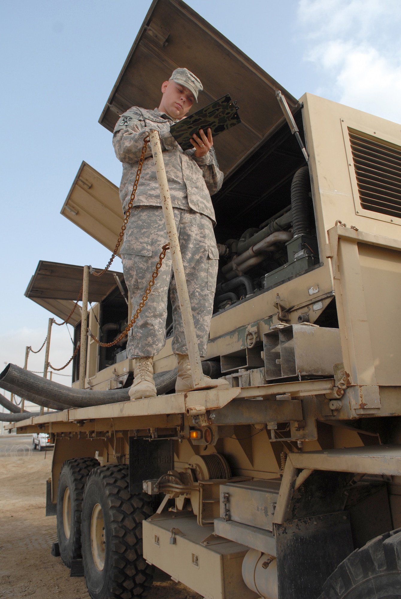Army Pvt. Justin Puerner conducts preventive maintenance checks and services on an electrical power plant vehicle Jan. 3 at an air base in Southwest Asia. Private Puerner is deployed to the Air Force's 380th Air Expeditionary Wing from 5-52 Air Defense Artillery Battalion of Fort Bliss, Texas. The vehicles support the first Army Patriot mission to be incorporated into the 380th Air Expeditionary Wing's mission. Private Puerner is from Green Bay, Wis. (U.S. Air Force photo/Tech. Sgt. Denise Johnson) 
