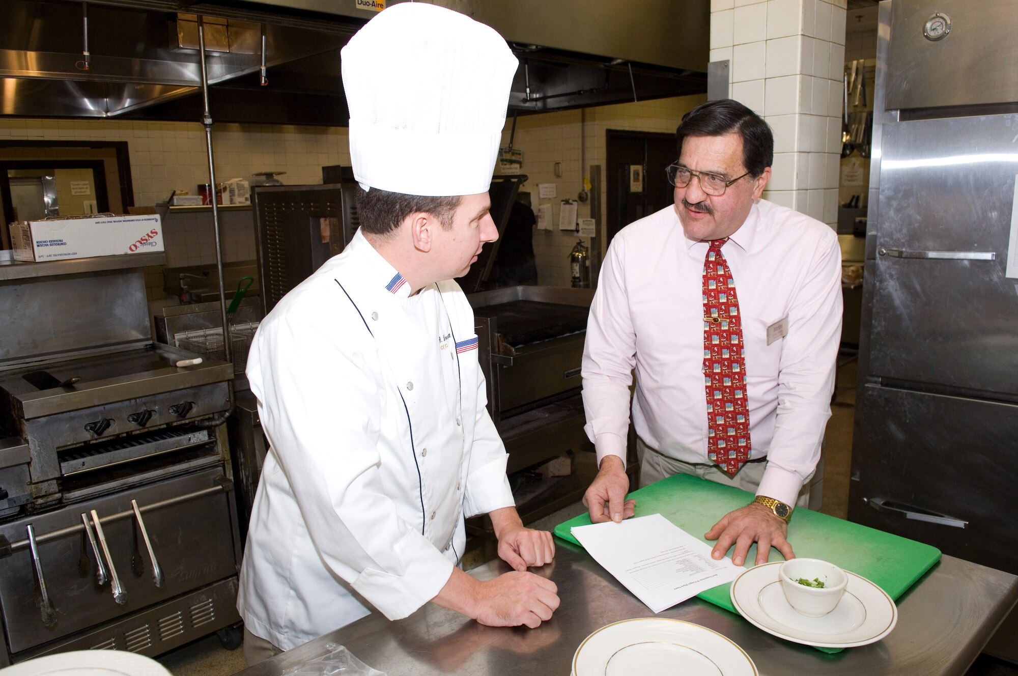 Senior Master Sgt. Mark Veomett and Minuteman Club Manager Dave Bovio review menu options for the Jan. 16 evening of gourmet dining at the club.  Limited tickets are available. (USAF photo by Rick Berry)