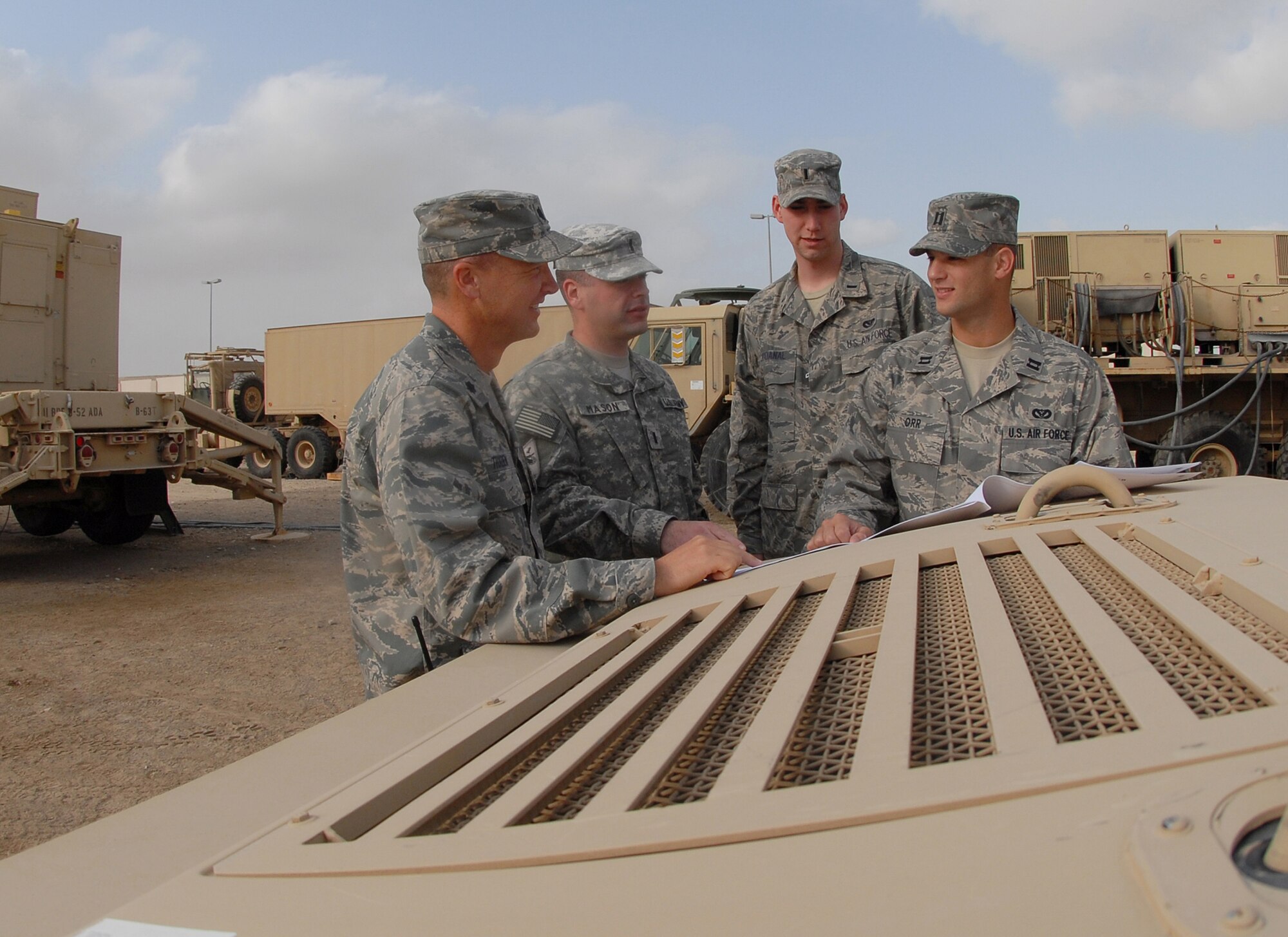SOUTHWEST ASIA - Airmen and Soldiers gather at the Patriot Battery motor pool to go over ground plans Jan. 3 in preparation for the arrival of about 200 Soldiers in the coming weeks. (Left to right) The 380th Expeditionary Mission Support Group deputy commander, Lt. Col. Fred Thaden; Army 1st Lt. Erik Mason, 5-52 Air Defense Artillery Battalion Signal Officer; 1st Lt. Shawn McDanal and Capt. Raymond Orr, both project officers with the 380th Expeditionary Civil Engineer Squadron, discuss site layout plans over the hood of an Army Patriot Battery communications vehicle. The advance team of Soldiers, in addition to the arrival of the main body, will comprise the first Patriot Battery at the 380th Air Expeditionary Wing. The Soldiers will be incorporated into the 380th AEW's mission in support of Operations Iraqi and Enduring Freedom and Joint Task Force Horn of Africa. Colonel Thaden hails from Colorado Springs, Colo. He is deployed from Hill Air Force Base, Utah, where his wife and children reside. Lieutenant Mason is deployed from Fort Bliss, Texas; he calls Olean, N.Y., home. Lieutenant McDanal, deployed from Andrews AFB, Md., hails from Conifer, Colo. Captain Orr, a Downingtown, Pa., native, recently returned to his home station of Moron Air Base, Spain. Captain Orr was the lead engineer for the Army bed-down prior to handing the reins over to new arrival, Lieutenant McDanal. (U.S. Air Force photo by Tech. Sgt. Denise Johnson) (released)