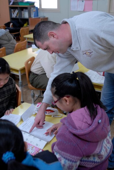 A Wolf Pack member helps a Korean schoolchild write in English. Kunsan Airmen regularly volunteer to teach English to local children. The program is part of United States Forces Korea's Good Neighbor Program.