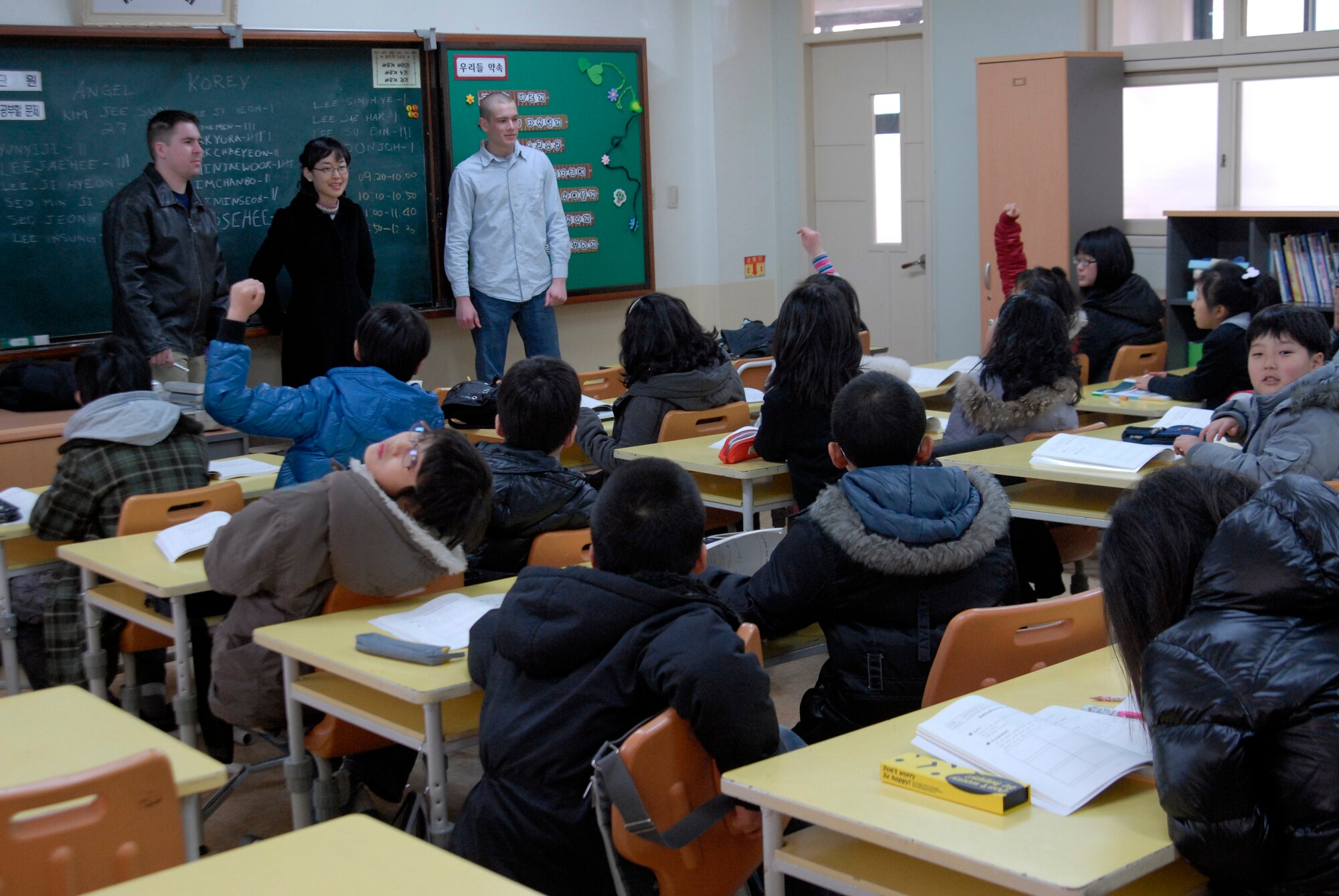 Korean schoolchildren raise thir hands before asking questions of the Wolf Pack volunteer English teachers. Kunsan Airmen regularly volunteer to teach English to local children. The program is part of United States Forces Korea's Good Neighbor Program.