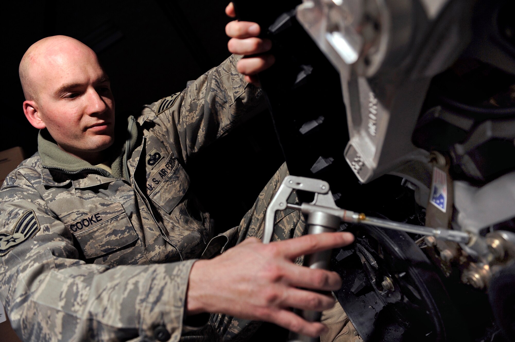 Staff Sgt. John Cooke, 28th Security Forces Squadron assistant NCO in charge of mobility, applies grease to the wheel assembly of a rubber track conversion system Jan. 6, here.  The tracks are capable of travel over snow, sand and swamp-covered terrains. (U.S. Air Force photo/Senior Airman Marc I. Lane)