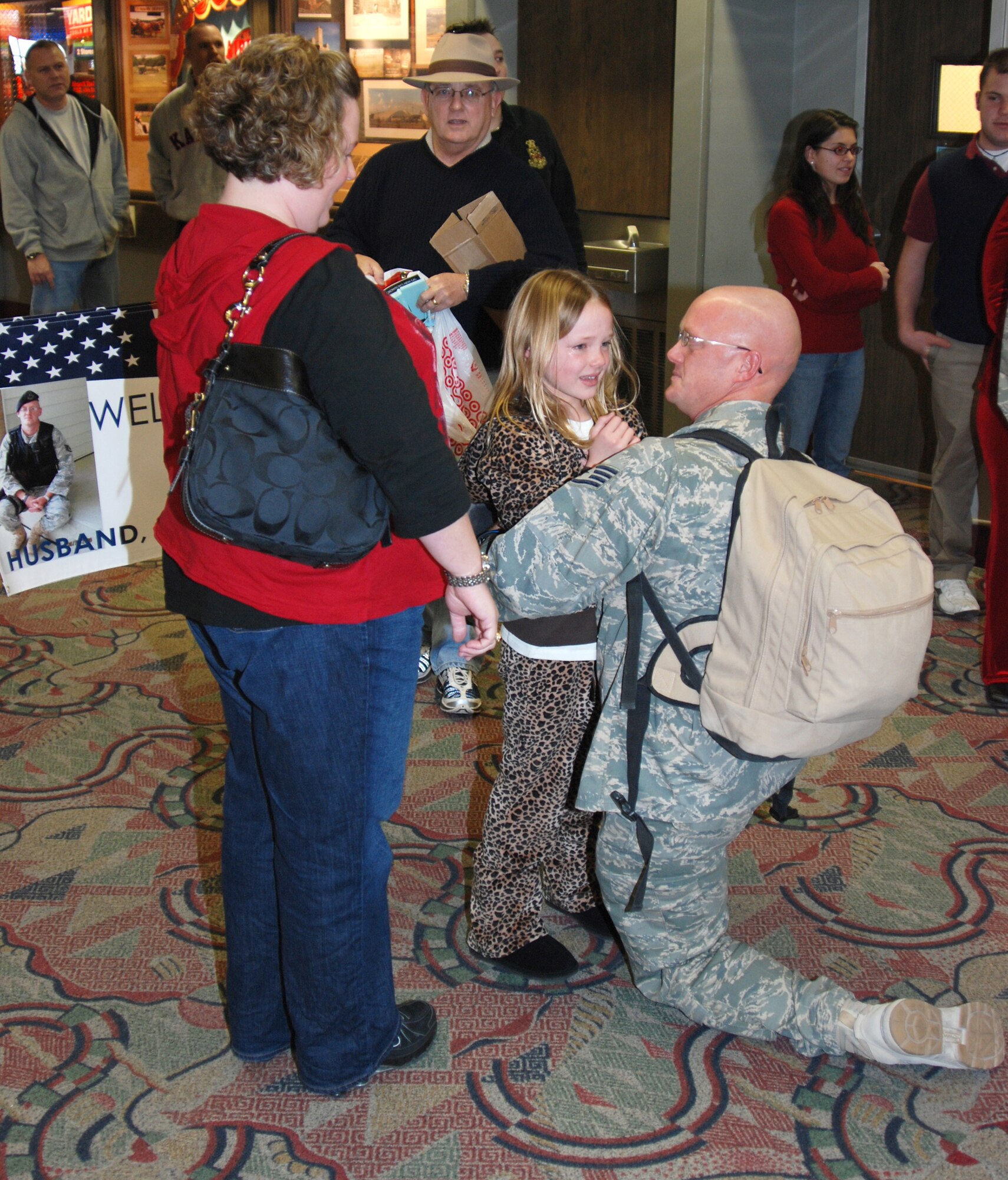 WICHITA, Kan. -- Staff Sgt. James Sanders, 22nd Security Forces Squadron, embraces his eight-year-old daughter, Kaitlyn, and his wife, Charity, Dec. 25, after arriving at Wichita Mid-Continent Airport two weeks before his originally schedule return date from his deployment to Al Udeid Air Base, Qatar. Twelve other security forces defenders also returned home as part of a rotation of Airmen who provided security for the base. (Photo by Airman 1st Class Jessica Lockoski) 
