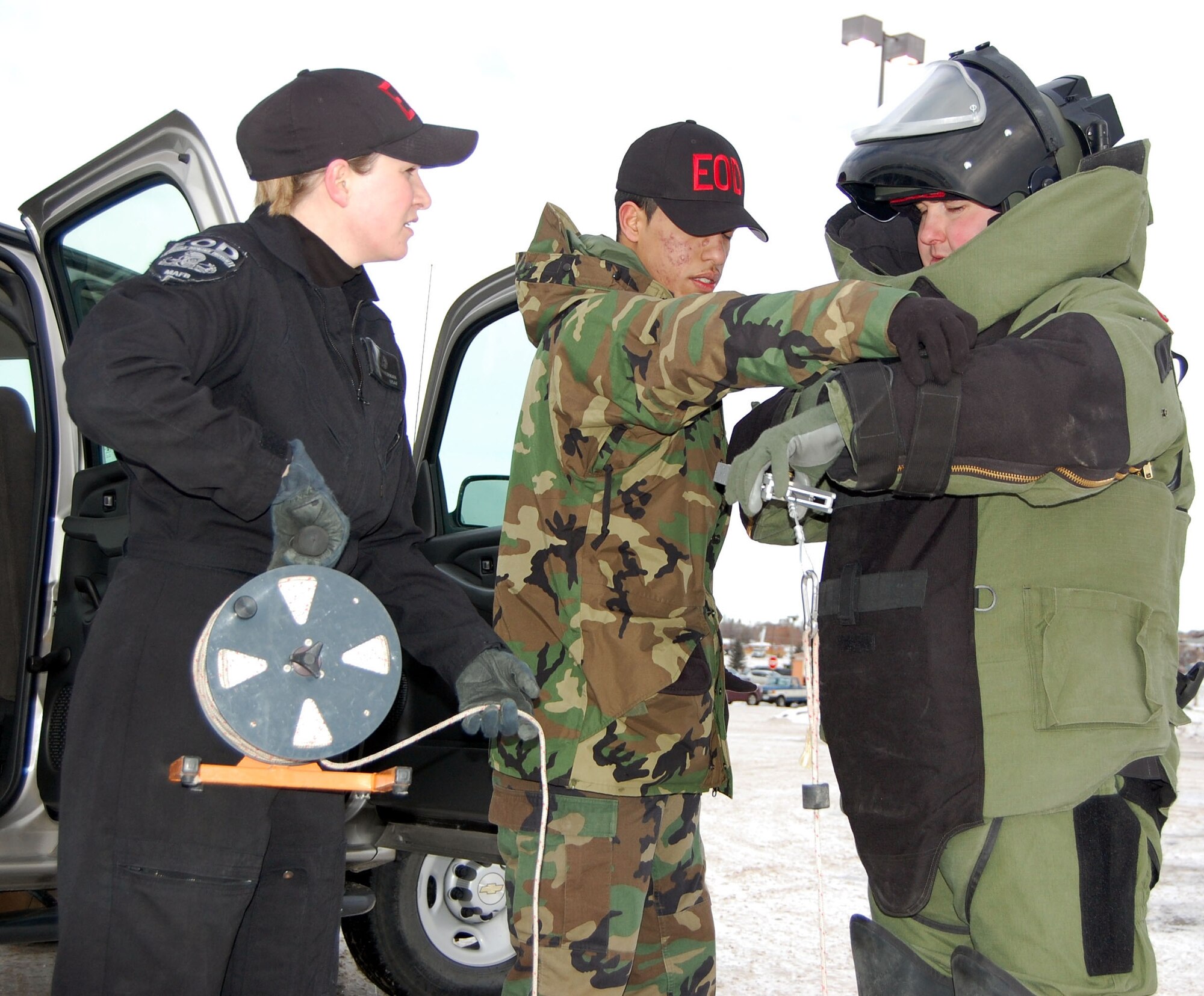 Senior Airman Kelly Zimmerman and Airman 1st Class Javier Martinez, help Staff Sgt. Daniel Hunsinger suit-up in an explosive ordnance disposal bomb suit Jan. 5 in Great Falls, Mont. The EOD team was called out to investigate a suspicious package at a bank off-base.  Once the situation was clear, the bank was re-opened for business. The Airmen are 341st Civil Engineer Squadron EOD technicians stationed at Malmstrom Air Force Base, Mont.  (U.S. Air Force photo/Staff Sgt. Eydie Sakura)