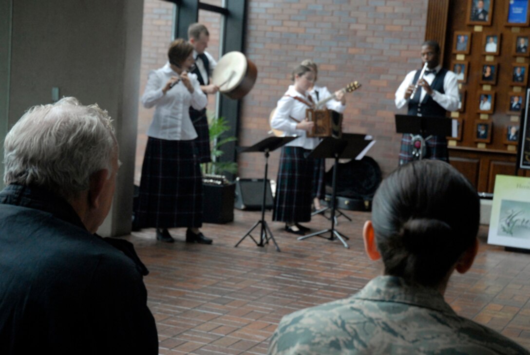 Bobby Pierce and Staff Sgt. Dina Maldonado listen to the holiday caroling sounds of the Heritage Aire Celtic Ensemble, Langley AFB, VA. at the wing headquarters building Dec. 10. The Air Combat Command band performed for Airmen, family members, civilian employees and retirees around the base by blending traditional music of Ireland, Scotland and England with a contemporary musical style creating a stunning musical tapestry. Sergeant Maldonado is assigned to the 437th Airlift Wing and Mr. Pierce is a member of the 437th Operation Support Squadron. (U.S. Air Force photo/Tech. Sgt. David Watson)