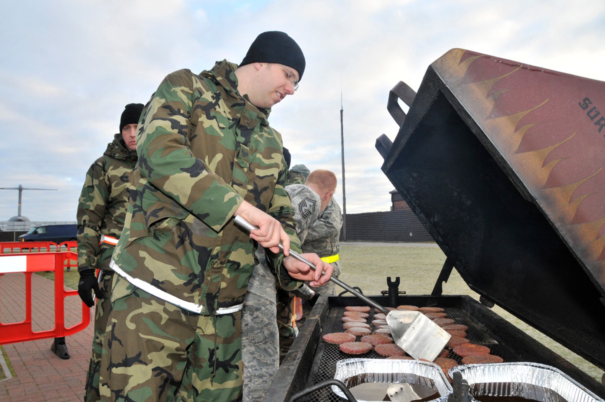 Staff Sgt. David Folger, 48th Equipment Maintenance Squadron, cooks hamburgers and hot dogs outside the unit deplyment facilty, Jan. 3 at RAF Lakenheath, England. Airmen volunteered to cook food for the deploying Airmen before they get on the plane. (U.S. Air Force photo by Airman 1st Class Perry Aston)