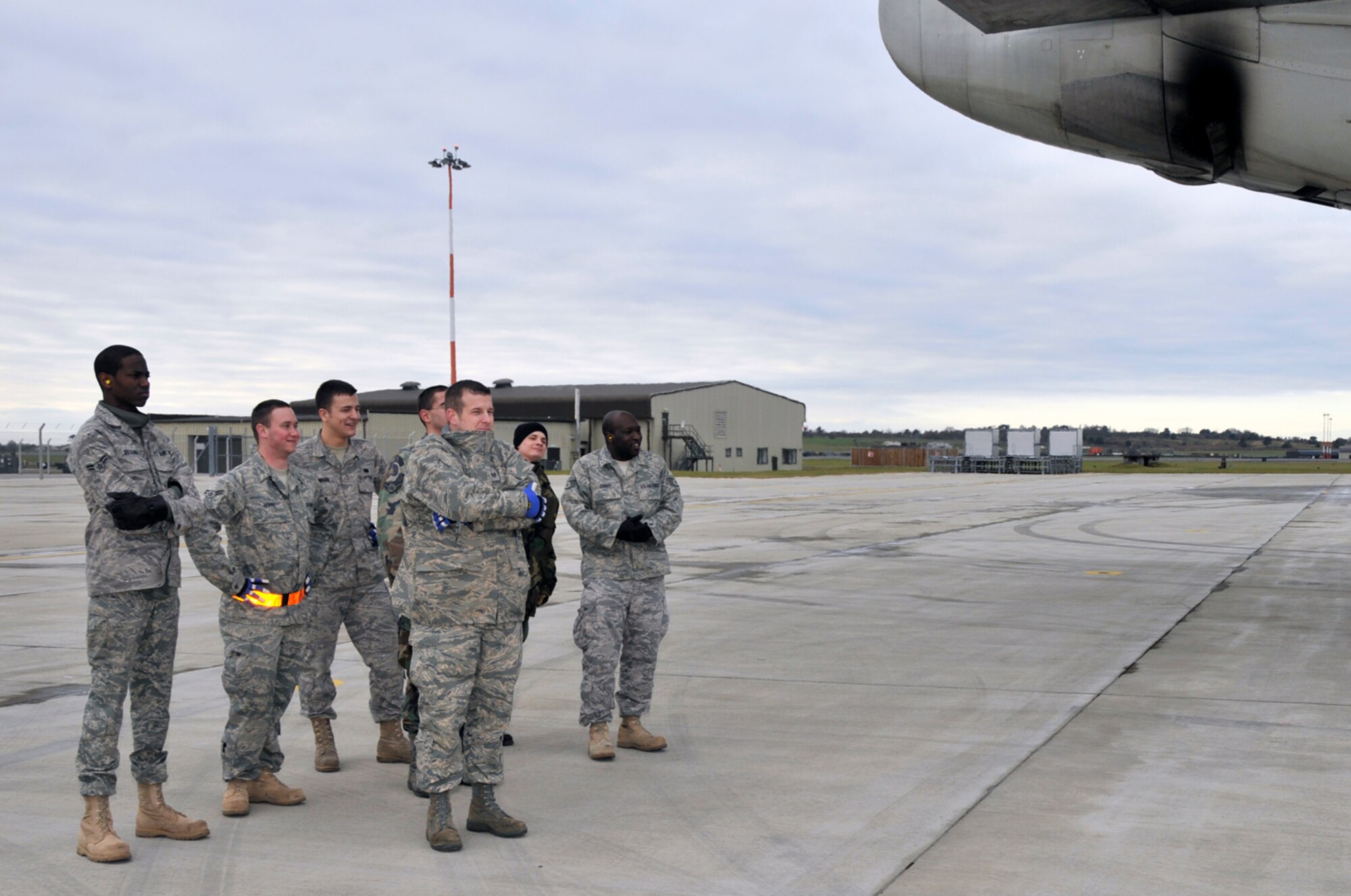 Airmen use the exhaust from the MD-11 to keep warm while they wait for the deployers' luggage to arrive so it can be loaded on the plane, Jan. 3 at RAF Lakenheath, England. More than 300 Airmen from the 48th Fighter Wing deployed in support of Operation Enduring Freedom. (U.S. Air Force photo by Airman 1st Class Perry Aston)