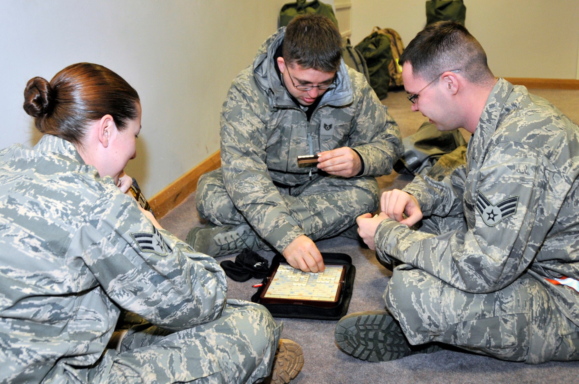 Staff Sgt. Chad Gartman, Senior Airman Virgina Beck and Senior Airman Joel Kitts, 48th Munitions Squadron storage crew chiefs, play a game to pass the time while they wait for the buses to take them to the unit deployment facility, Jan. 3 at RAF Lakenheath, England. More than 300 Airmen from the 48th Fighter Wing deployed in support of Operation Enduring Freedom. (U.S. Air Force photo by Airman 1st Class Perry Aston)