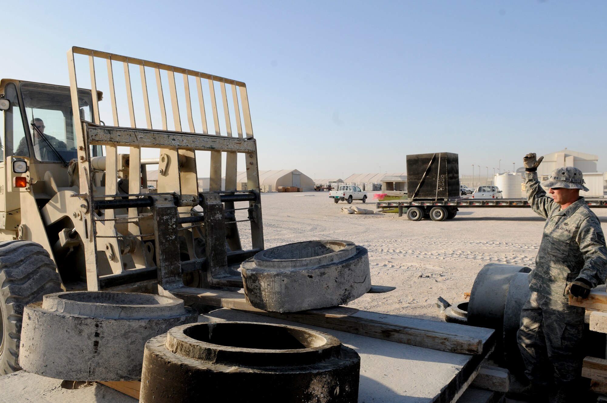 Staff Sgt. Rodney Atkins, a pavement maintenance and construction equipment craftsman (Dirt Boyz) assigned to the 379th Expeditionary Civil Engineer Squadron, directs Airman 1st Class Shawn Rivere, a Dirt Boyz apprentice, loading manhole covers onto a pallet with a 10K forklift, Jan. 6, 2008, at an undisclosed air base in Southwest Asia. They're called the Dirt Boyz, for a good reason: while much of the base is comfortable indoors, they're out getting dirty - paving roads and air strips, repairing fences and other structures, operating heavy equipment, and sweeping for foreign object debris.  Sergeant Atkins is a native of Kingsburg, Calif., and deployed from Travis Air Force Base, Calif.  Airman Rivere hails from New Orleans, La., and is deployed from Yakota Air Base, Japan; both are supporting Operation Iraqi and Enduring Freedom and Joint Task Force-Horn of Africa.  (U.S. Air Force photo by Tech. Sgt. Michael Boquette/Released)