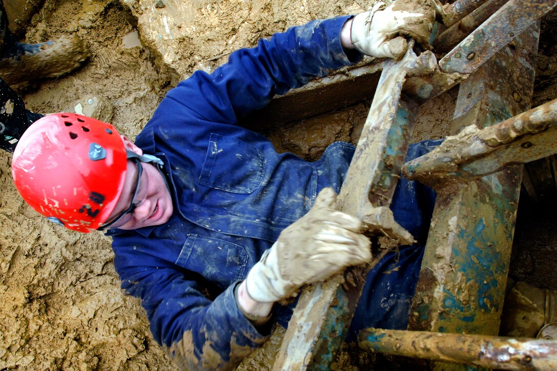 U.S. Marine Corps Pfc. John Michaud slides under a steel grate through