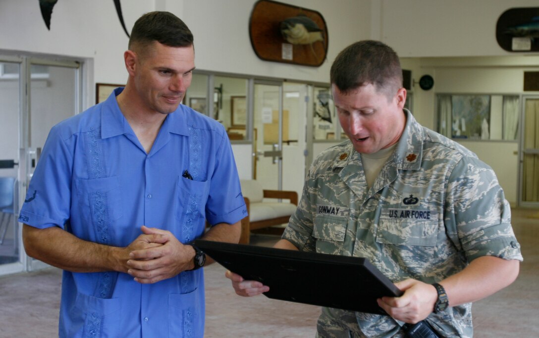 Air Force Maj. Jerome T. Conway, right, Wake Island's base commander, reads from a plaque before presenting it and an American flag flown on the island to Lt. Col. Vance L. Cryer, commanding officer of Marine Attack Squadron 211, shortly after approximately 60 Marines and eight AV-8B Harriers landed there on Jan. 8, 2009. The return of VMA-211 to the remote Pacific atoll marks the first time since May 1993 the bulk of the squadron, nicknamed the "Wake Island Avengers," has returned to its symbolic birthplace where a handful of the unit's Marines helped defend the island from an overwhelming Japanese invasion force from Dec. 8-23, 1941, before its surrender. The squadron flew to Iwakuni, Japan, two days later and attached to the 31st Marine Expeditionary Unit for a seven- to nine-month deployment. VMA-211 is based in Yuma, Ariz. (Photo by Gunnery Sgt. Bill Lisbon)