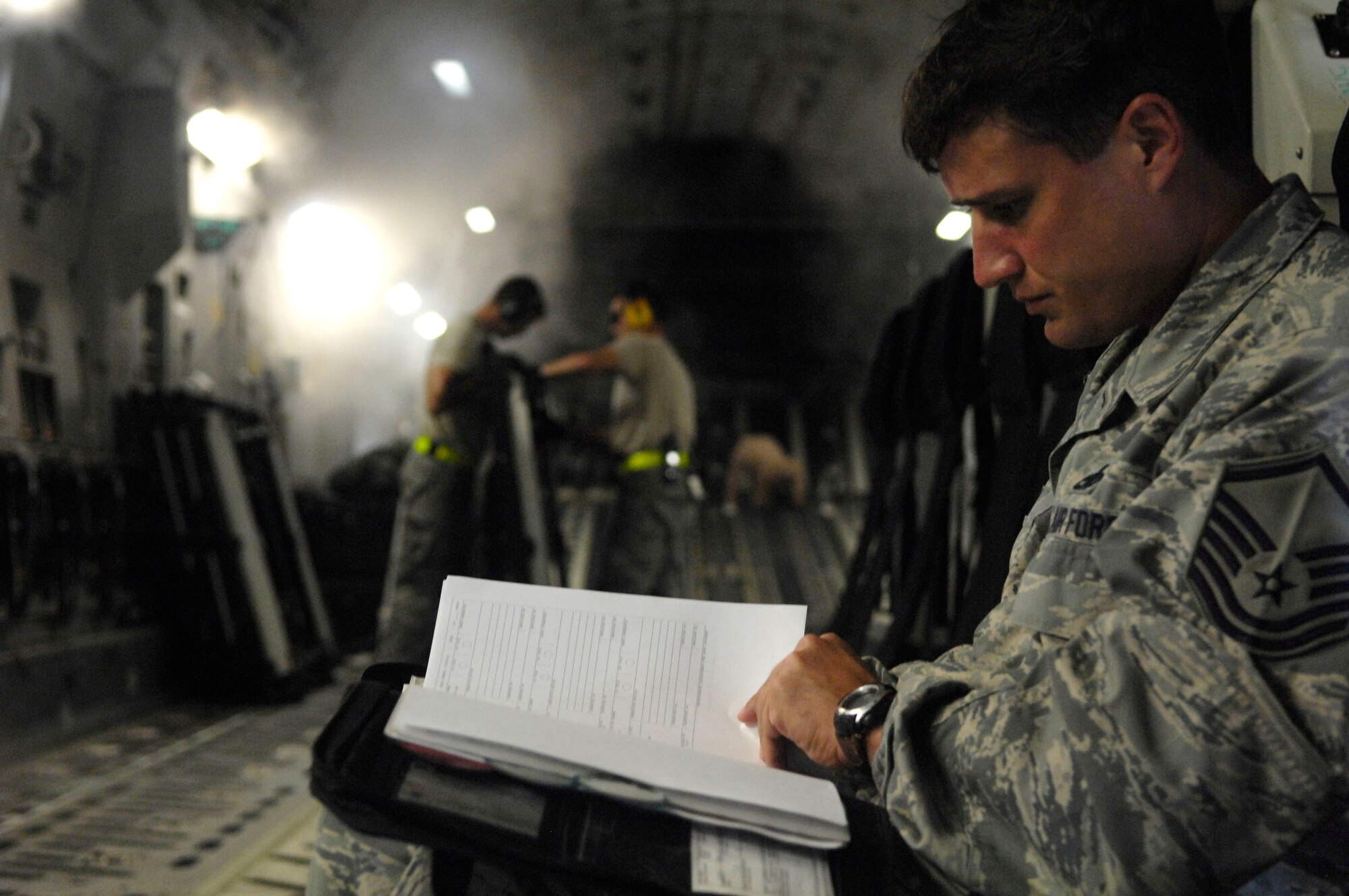 Master Sgt. Daniel Buse reviews forms in a C-17 Globemaster III en route to Afghanistan. Sergeant Buse is assigned to the 734th Air Mobility Squadron from Andersen Air Force Base, Guam. (U.S. Air Force photo/Tech. Sgt. Cohen A. Young) 
