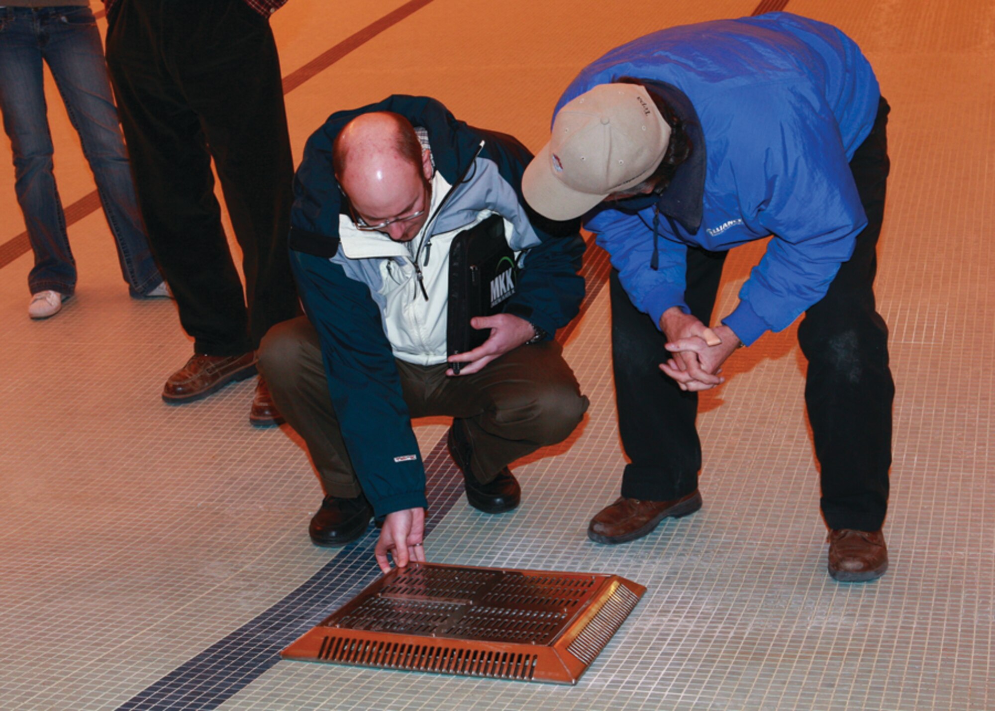 Patrick Davis, a mechanical engineer from a local consulting company, and Randy Tiley, site manager for Torix General Contractors, inspect the drain cover Dec. 24 at the aquatic center prior to installation. (Photo by Jeff Allred)