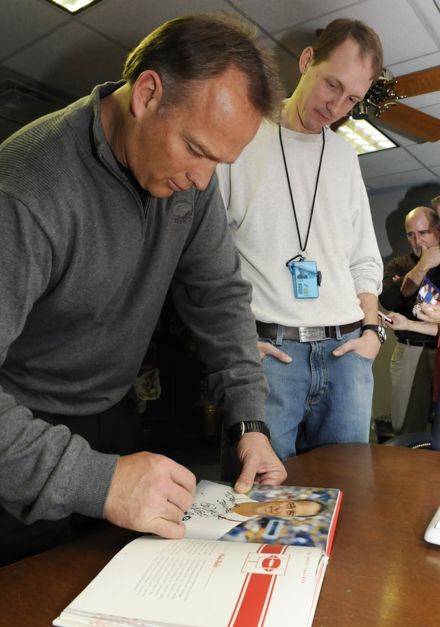 Coach Mark Richt, head coach for the University of Georgia Bulldogs, signs an autograph for fan Jason Fulton, an employee in the Defense Distribution Depot Warner Robins.  Coach Richt was at Robins to sign autographs and greet fans in the DDWG, where Sharon Potts works as a program analyst. The Bulldogs are recruiting Mrs. Potts’ son Abry Jones, a defensive lineman at Northside High School. U. S. Air Force photo by Sue Sapp