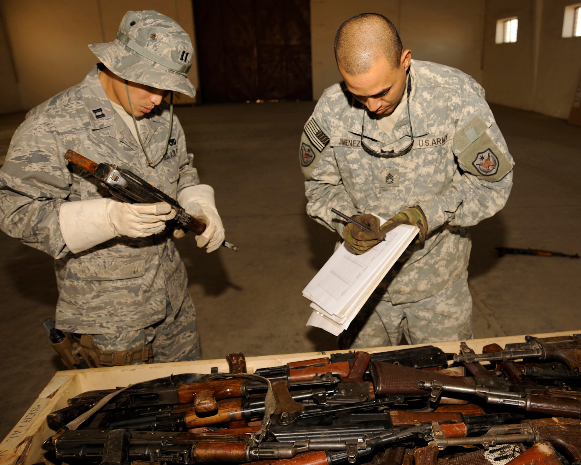Capt. Ted Yang calls out the serial number of an AK-47 rifle to Army Sgt. 1st Class Alejandro Jimenez as he records the number at Taji Military Base, Iraq. All captured enemy weapons are accounted for before they are packaged up and shipped to be destroyed. Captain Yang is the J4 Taji liaison officer. He is a native of Fresno, Calif., and deployed from Whiteman Air Force Base, Mo. Sergeant Jimenez is the Multinational Security Transition Command-Iraq J4 collective weapons point NCO in charge. (U.S. Air Force photo/Staff Sgt. Paul Villanueva II) 
