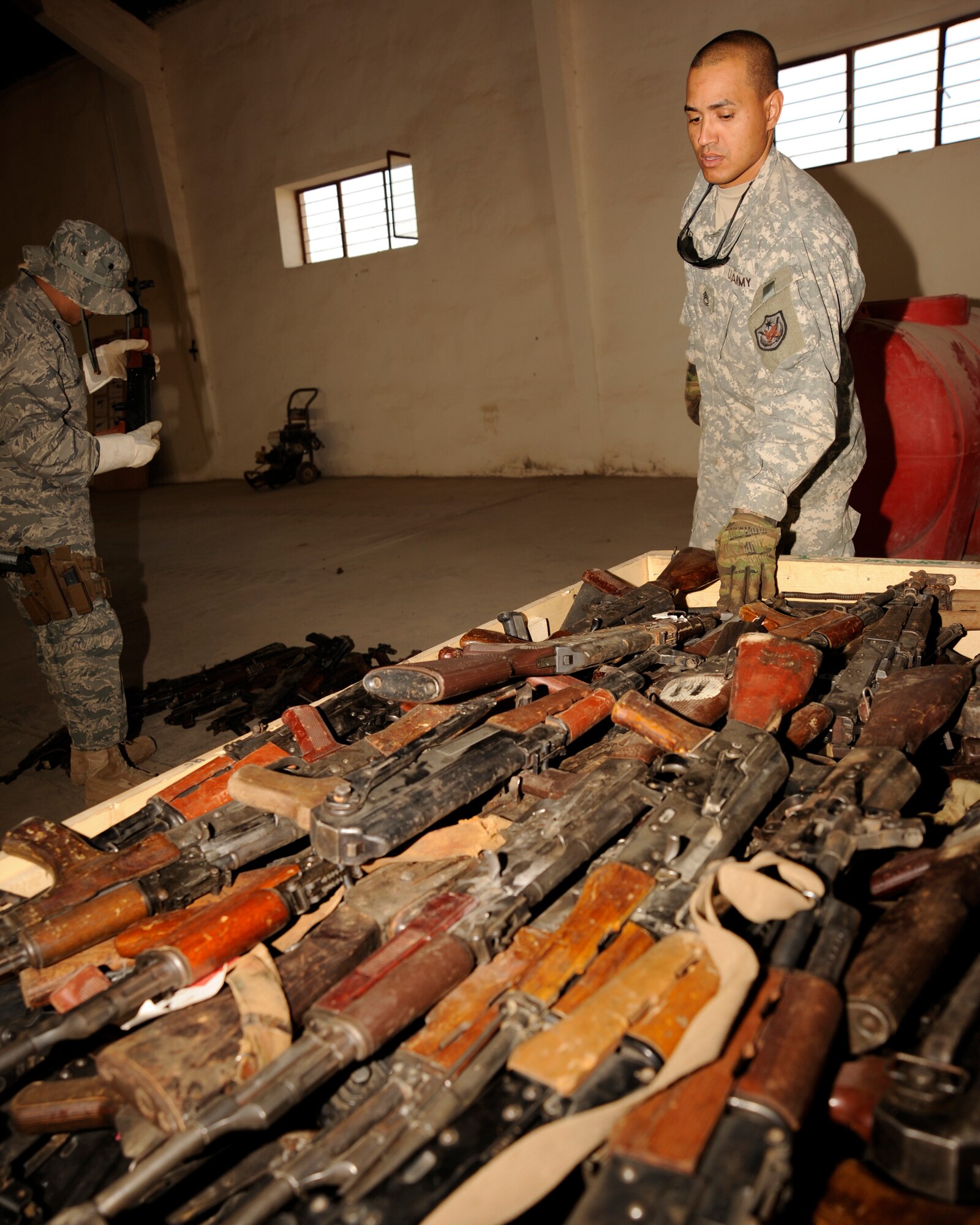 TAJI, Iraq -- Army Sgt. 1st Class Alejandro Jimenez, Multi-National Security Transition Command - Iraq J4, Collective Weapons Point non-commissioned officer in charge, places AK-47 rifles into a shipping crate at Taji Military Base, Iraq. The captured enemy weapons are accounted for and then shipped out to be destroyed. Jimenez, a Patchogue, N.Y. native, is deployed from the U.S. Army Europe, 7th Army, Heidelberg, Germany. (U.S. Air Force photo/Staff Sgt. Paul Villanueva II)