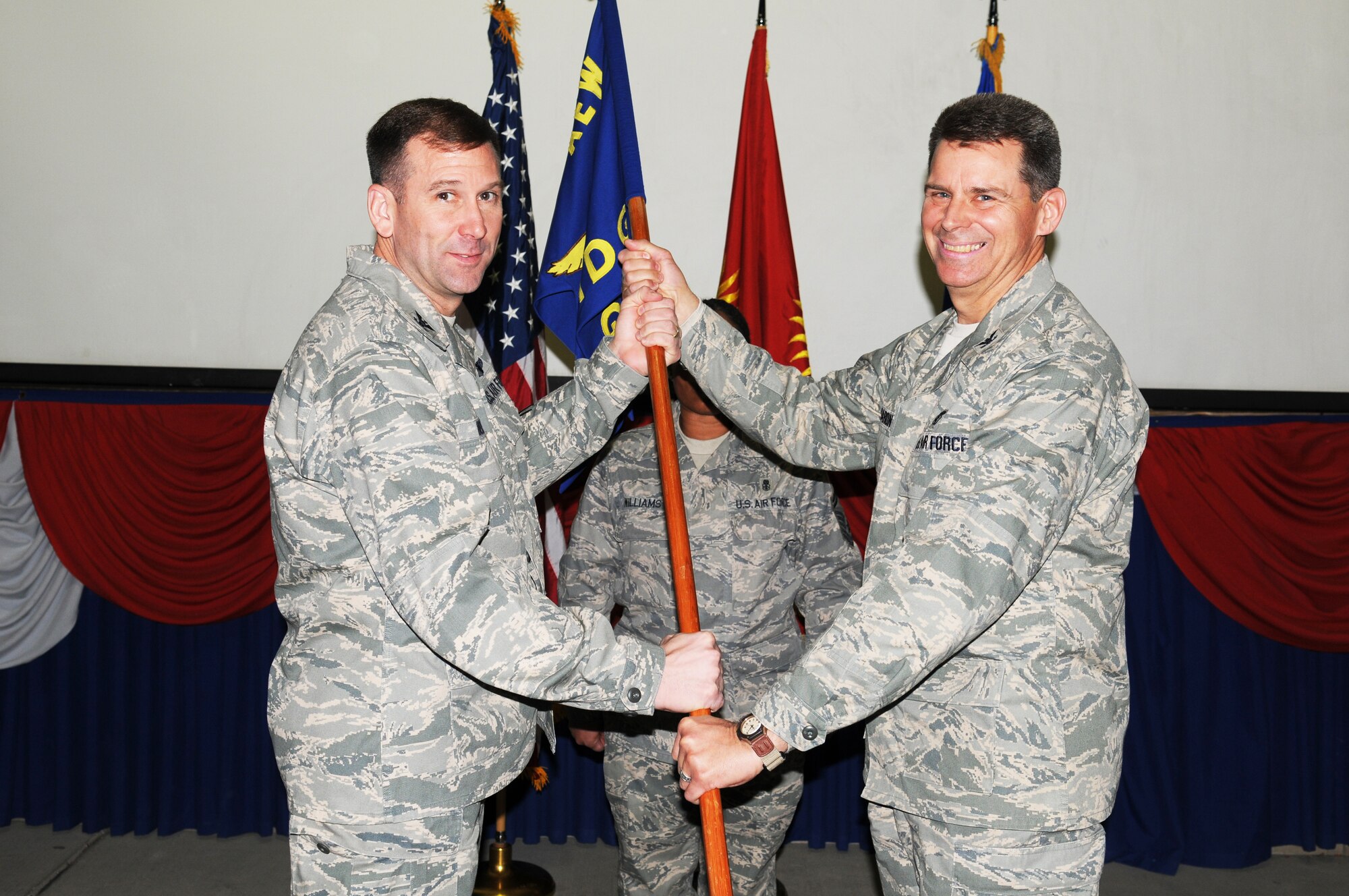 MANAS AIR BASE, KYRGYZ REPUBLIC -- Col. Gerard Caron (right) accepts the 376th Expeditionary Medical Group guidon from Col. Christopher Bence, 376th Air Expeditionary Wing commander, during a change of command ceremony here, Jan. 7. Colonel Caron assumed command of the 376th EMDG from Col. Roosevelt Allen Jr., who returned to Minot Air Force Base, N.D., following a four-month deployment to Manas AB. Colonel Caron is deployed from Randolph AFB, Texas, where he serves as the Deputy Command Surgeon for Air Education and Training Command. (Air Force photo / Senior Airman Ruth Holcomb)