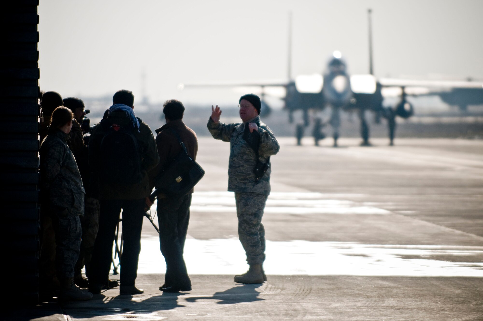 Capt. Tom Wenz, 455th Air Expeditionary Wing public affairs officer, briefs Afghan media on close air support while an F-15E Strike Eagle is disarmed in the background at Bagram Air Field, Afghanistan, Jan. 5. Members of the Afghan media were invited on base to learn about the 455th AEW close air support mission. (U.S. Air Force photo by Staff Sgt. Samuel Morse)(released)