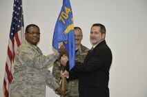 Col. Raytheon Scott, 704th Maintenance Group commander, hands the squadron flag to James Myers, the new 704th Maintenance Squadron director. (Photo by Rick Goodfriend)