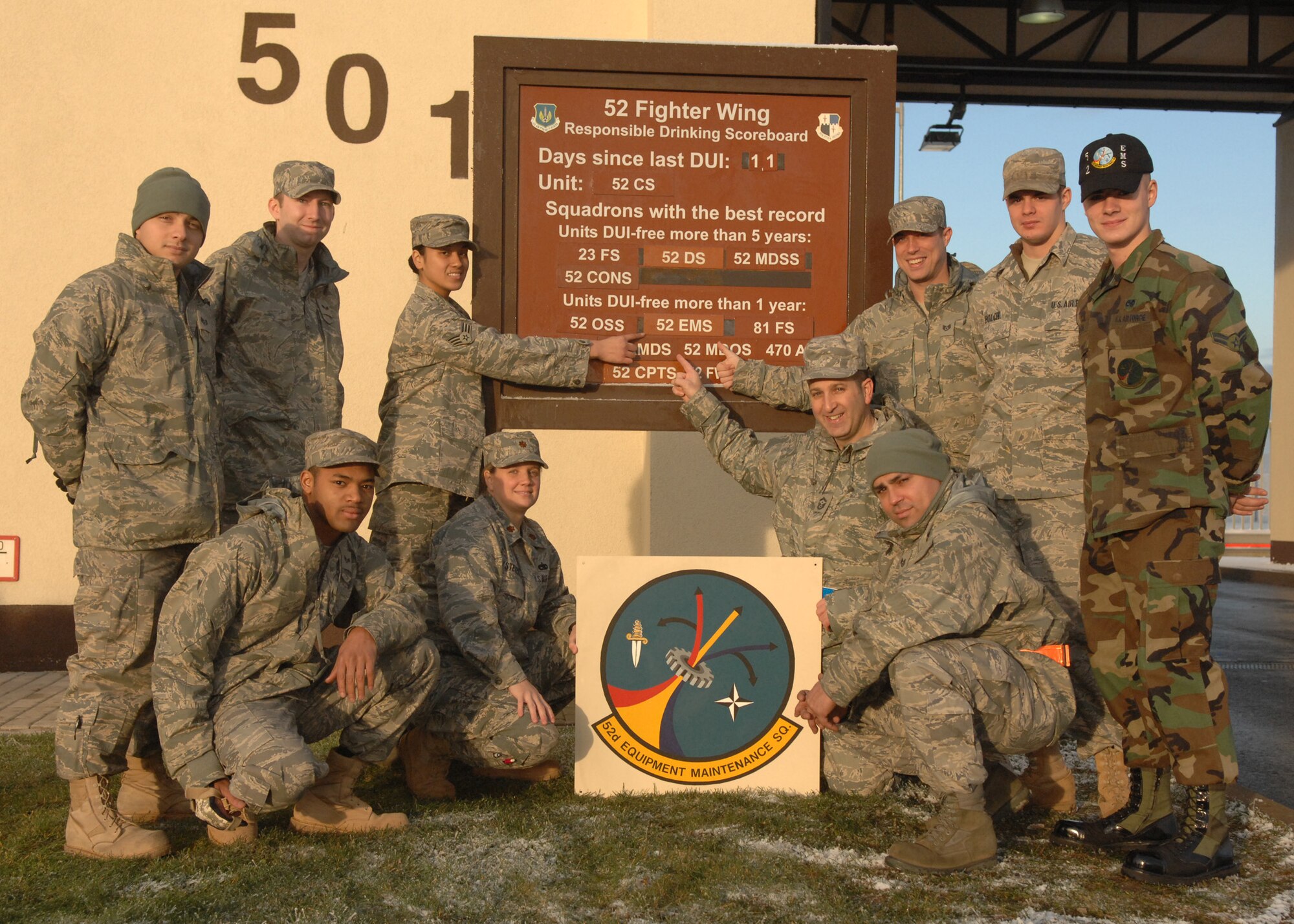 SPANGHDALEM AIR BASE, Germany -- Members of the 52nd Equipment Maintenance Squadron point to their unit’s name on the 52nd Fighter Wing Responsible Drinking Scoreboard, Dec. 12, 2008, to signify their unit going one year without having a driving while under the influence incident. (U.S. Air Force photo by Airman Staci Miller)