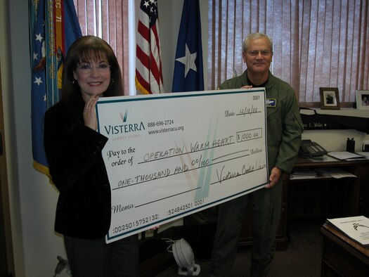 Michelle Lemoine, Visterra Credit Union’s business development director, presents a $1,000 check for Operation Warm Heart to Brig. Gen. James Melin, 452 AMW commander, in December at the base. Each year, Visterra has donated funds to help brighten the spirits of less fortunate military members during the holidays.(U.S. Air Force photo by Maj. Don Traud)