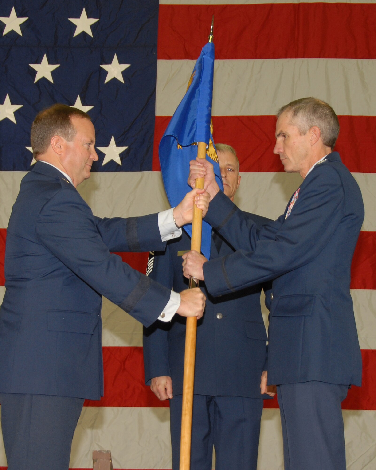 BG Don Haught hands the guidon to incoming Wing Commander Col Dennis Grunstad at the change of command ceremony for the 153d Airlift Wing