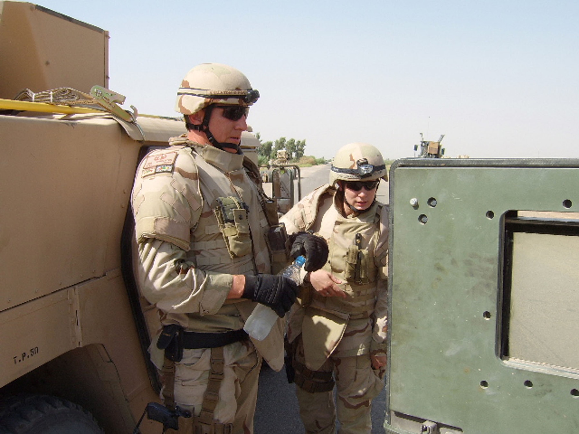 In an example of joint operations, U.S. Army personnel often protect USAF EOD technicians from enemy attack while they work. Here, an Army soldier providing security watches as Staff Sgt. Kimberly Mahan (right) operates the remote controls of a robot near Balad Air Base, Iraq, in 2006. (U.S. Air Force photo courtesy Staff Sgt. Kimberly Mahan)