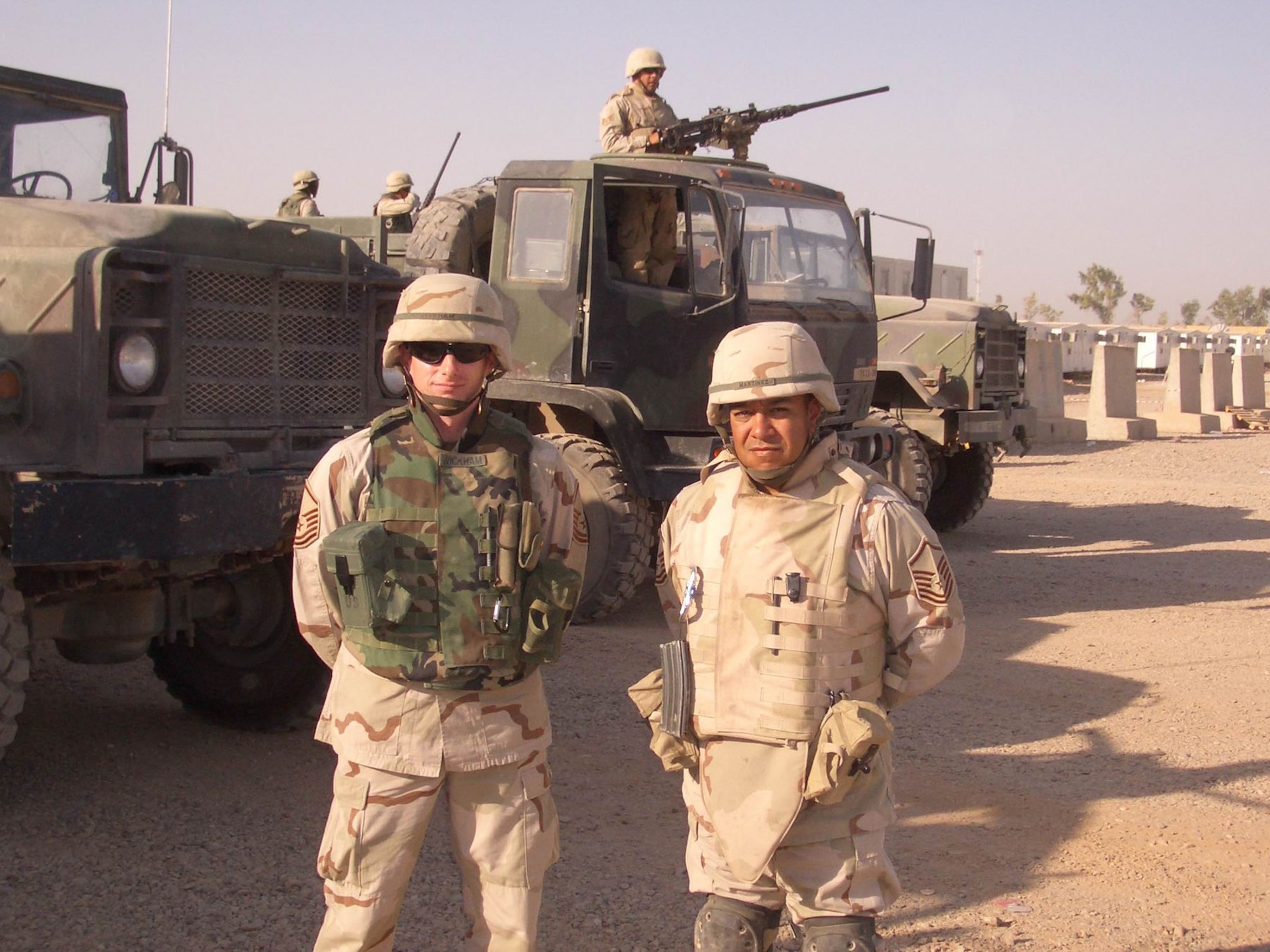 Convoy team members with body armor typically worn on missions.  In the background is one type of gun truck with a .50-cal machine gun position in the cab. (U.S. Air Force photo)