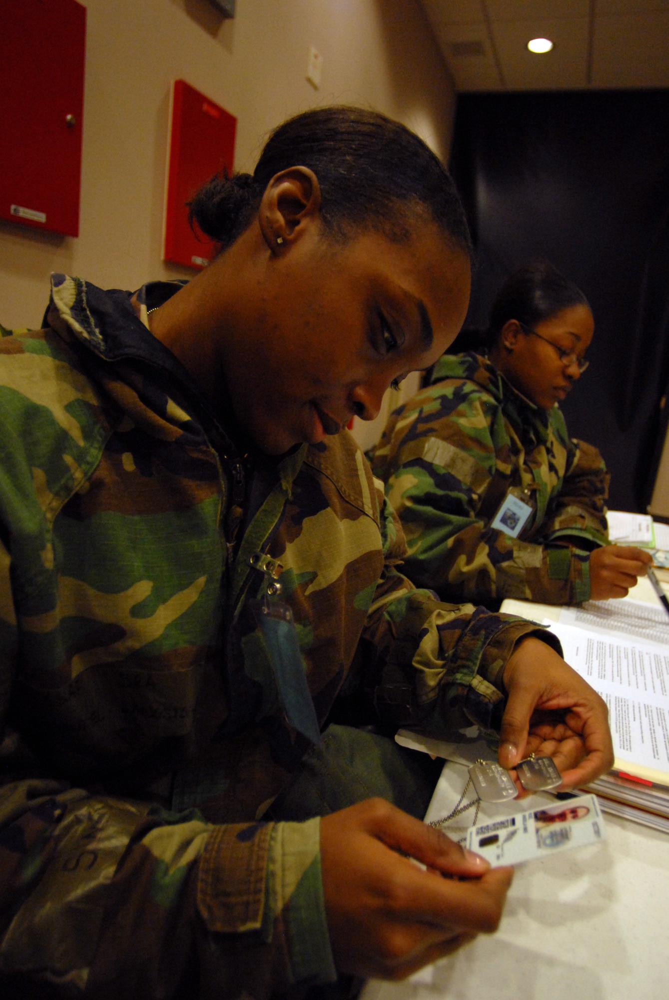 Senior Airman Shantel Langston, 8th Force Support Squadron, verifies an Airman's identification card against their "dog tags" as they process though the Personnel Deployment and Readiness Function line while Staff Sgt. Tiarra Brown, 8th Force Support Squadron, checks accountability. Both are participating in the Peninsula-Wide Operational Readiness Exercise Beverly Bulldog 09-01 at Kunsan Air Base, Republic of Korea, Jan. 12, 2009. The PDRF Line  is a key component in accepting any follow on forces to the wolf pack. (U.S. Air Force Photo by Senior Airman Angela Ruiz)  