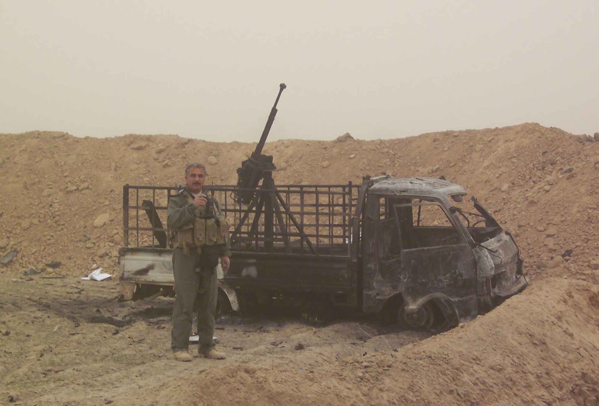 Local Iraqi SWAT commander standing next to an insurgent gun truck that was destroyed after the GBU-12 500-pound hit the trench next to the truck. The insurgents had several vehicle-mounted heavy machine guns. (U.S. Air Force photo)