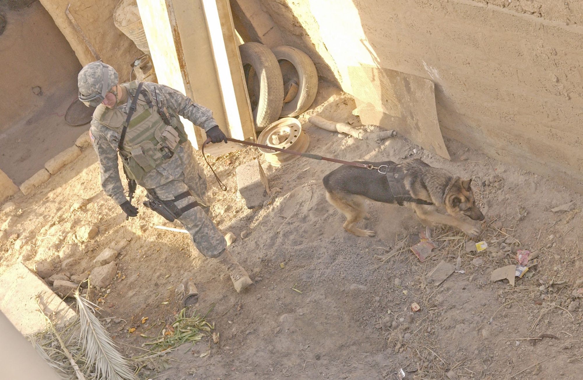 Air Force dog handler Senior Airman Daniel McClain, attached to the U.S. Army 25th Infantry Division, searches for explosive devices during a raid in Iraq in December 2006. (U.S. Air Force photo)