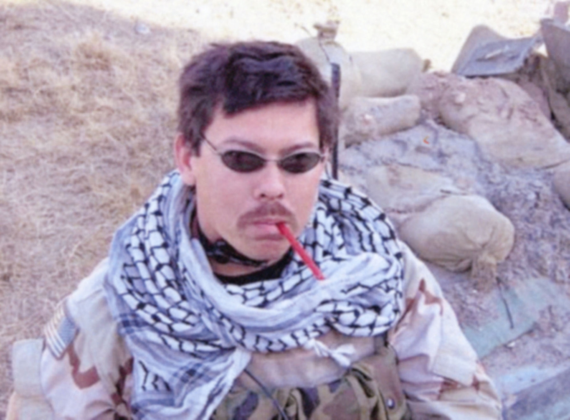 Staff Sgt. Rich Brake, JTAC who served three tours in Iraq, taking a moment to eat some candy just before a mission against a high value target in Samarra, Iraq in February 2005. He is wearing the keffiyeh (also called a shemagh) now on display at the National Museum of the United States Air Force. Keffiyehs are commonly worn in the Middle East to provide protection against the sun and blowing sand, and to identify one’s social position and group. (U.S. Air Force photo)