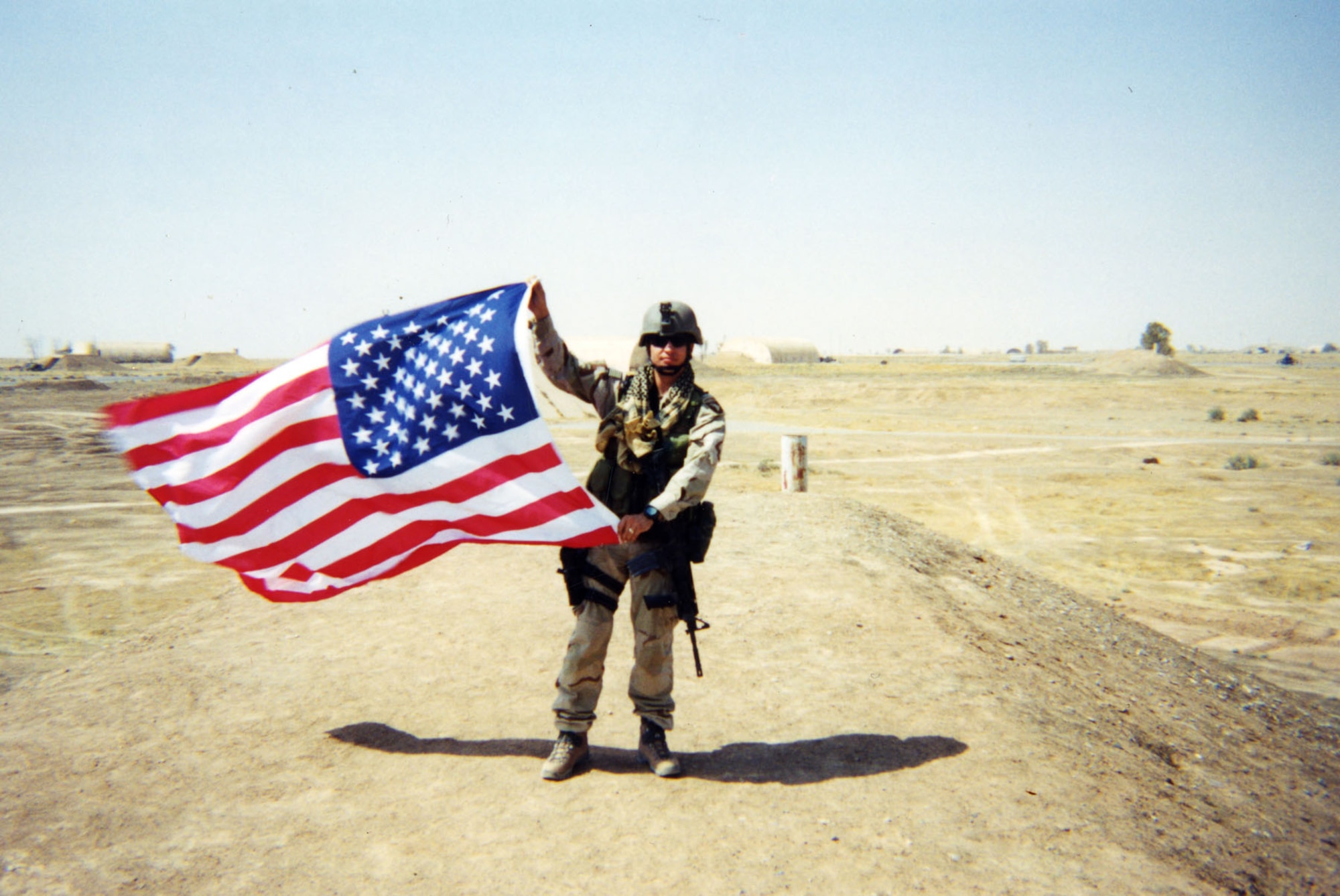 Staff Sgt. Sean Bailey waving a U.S. flag at “Q-West” (Qayyarah Airfield West), about 180 miles north of Baghdad. Bailey served two tours as a JTAC in Iraq. (U.S. Air Force photo)