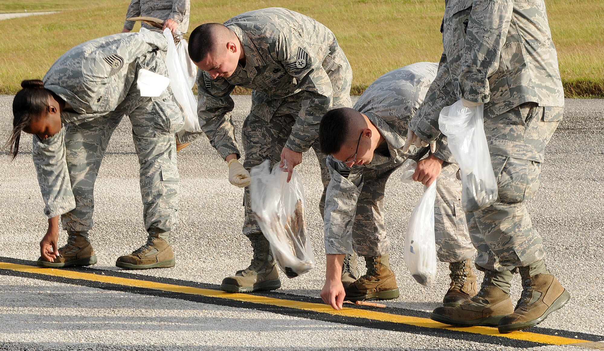 ANDERSEN AIR FORCE BASE, Guam - Members of Team Andersen pick up foreign object debris near the construction site of the Global Hawk Hangar during the mass FOD walk here Jan. 12 in preparation for the arrival of the F-22A Raptors. Twelve F-22's will arrive here for a three month deployment from Elmendorf Air Force Base, Alaska. The deployment support U.S. Pacific Command's theater security packages in the Western Pacific. (U.S. Air Force photo by Senior Airman Nichelle Griffiths)   