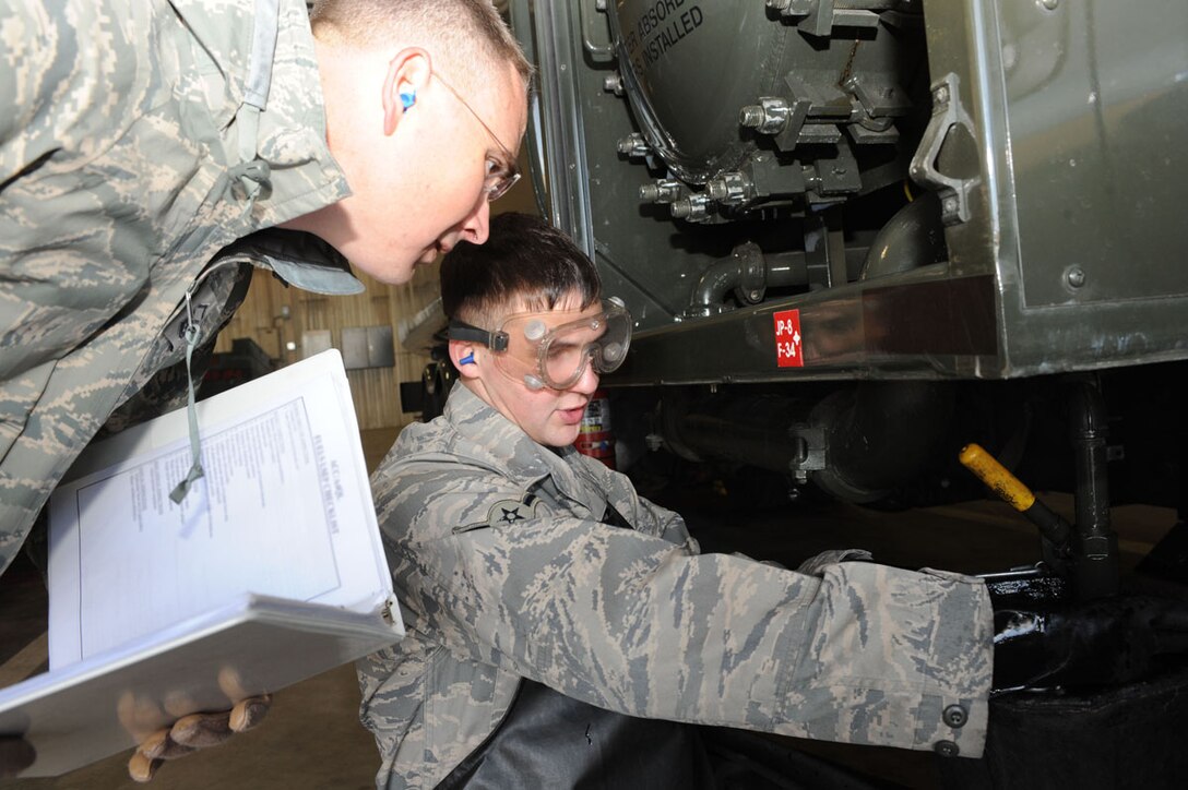 (Left) Master Sgt. Jon Voigt, Air Combat Command Logistics Standardization and Evaluation Team fuels superintendant, evaluates  Airman 1st Class Anthony Hareid, 28th Logistics Readiness Squadron fuels distribution journeyman, as he takes a sump sample here, Jan. 13. The sump sample is used to locate built-up water in the fuel separator. (U.S. Air Force photo/Airman 1st Class Adam Grant)
