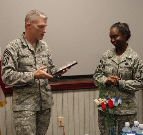 Chief Master Sgt. Robert Brooks, 99th Air Base Wing command chief master sergeant, presents Master Sgt. Andrea Cowper with a glass plaque with the Airman's Creed etched in it. The plaque was a farewell gift to Master Sgt. Cowper, who was selected as the newest adminstrative assistant to the secretary of the Air Force (U.S. Air Force photo by Tech. Sgt. Jillian Swanson)