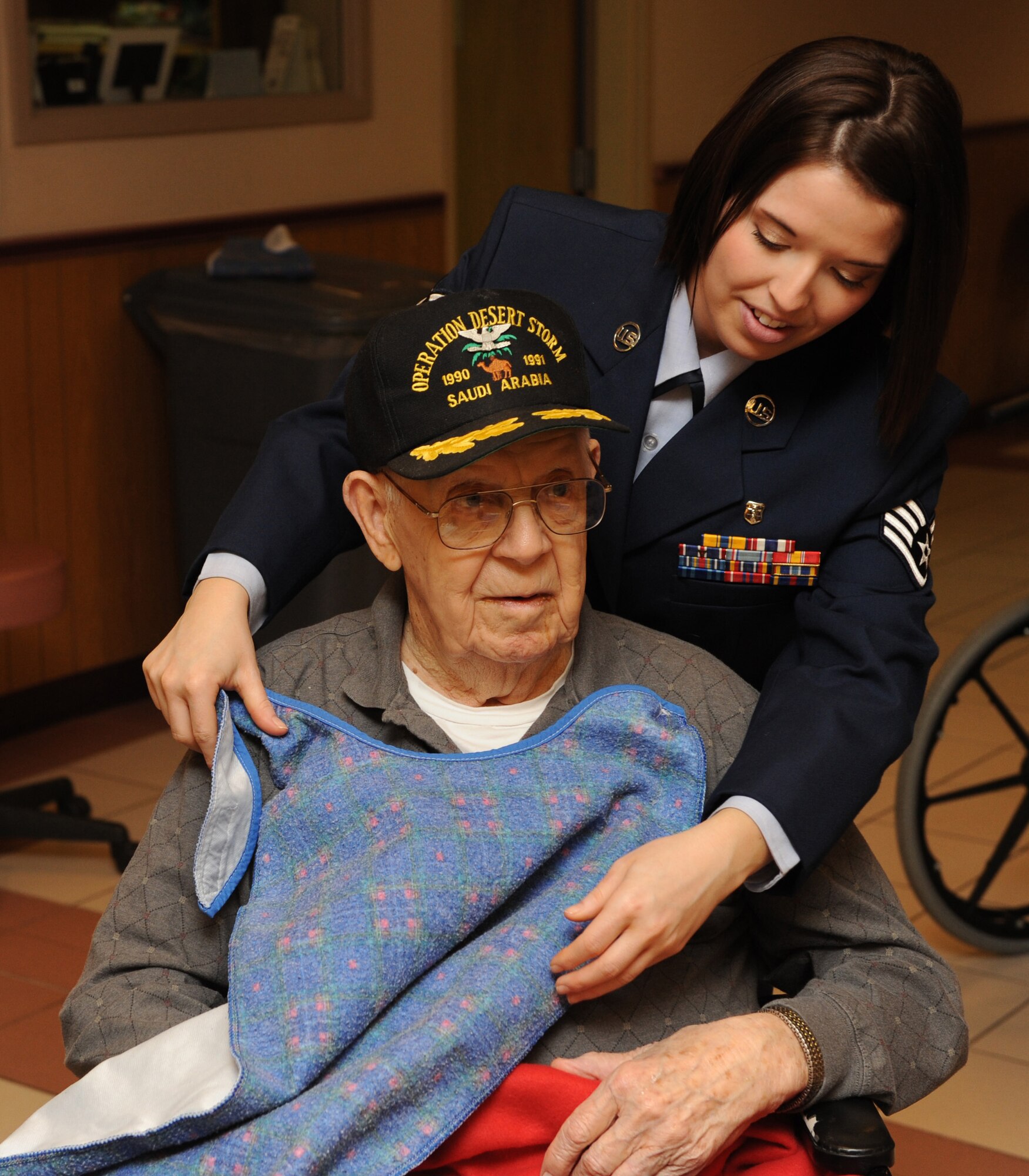 MOUNTAIN HOME AIR FORCE BASE, Idaho -- Staff Sgt. Holly Young, 366th Medical Squadron optometry technician, helps veteran Franklin Smith get ready for lunch at the Idaho State Veteran's Home Dec. 16. Airmen from Mountain Home Air Force Base traveled to the Idaho State Veteran's Home in Boise for a holiday visit. The group, Airmen for American Veterans, began the day inviting veterans to bingo, after which they helped serve lunch. (U.S. Air Force photo/ Airman 1st Class Debbie Lockhart)