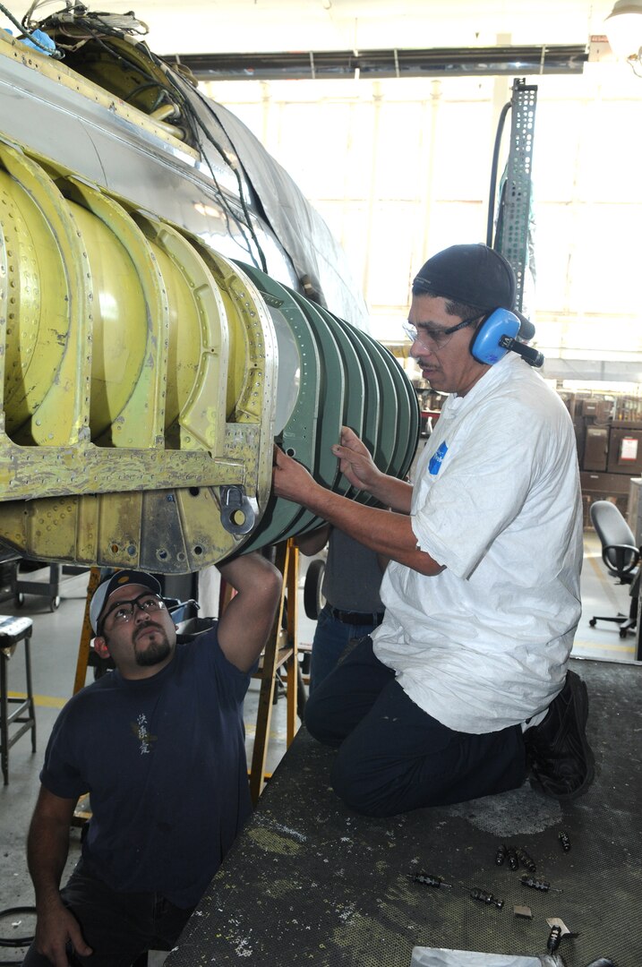 Rudy Martinez (right) and Marcus Travino, Lear Siegler Inc. contractors, install the air intake assembly on the engine of a T-38 at the Queen Bee facility at Randolph Air Force Base, TX. Queen Bee is the only heavy maintenance provider for the T-38 fleet, providing support of T-38 inspection, maintenance and modification requirments continuously for more than 30 years. (US Air Force photo by Rich McFadden) 